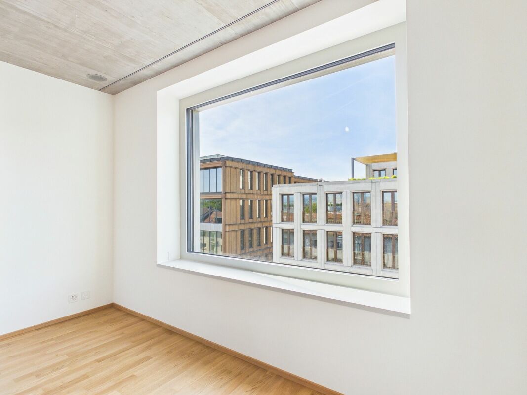 Helles, leeres Zimmer mit großem Fenster und Stadtblick