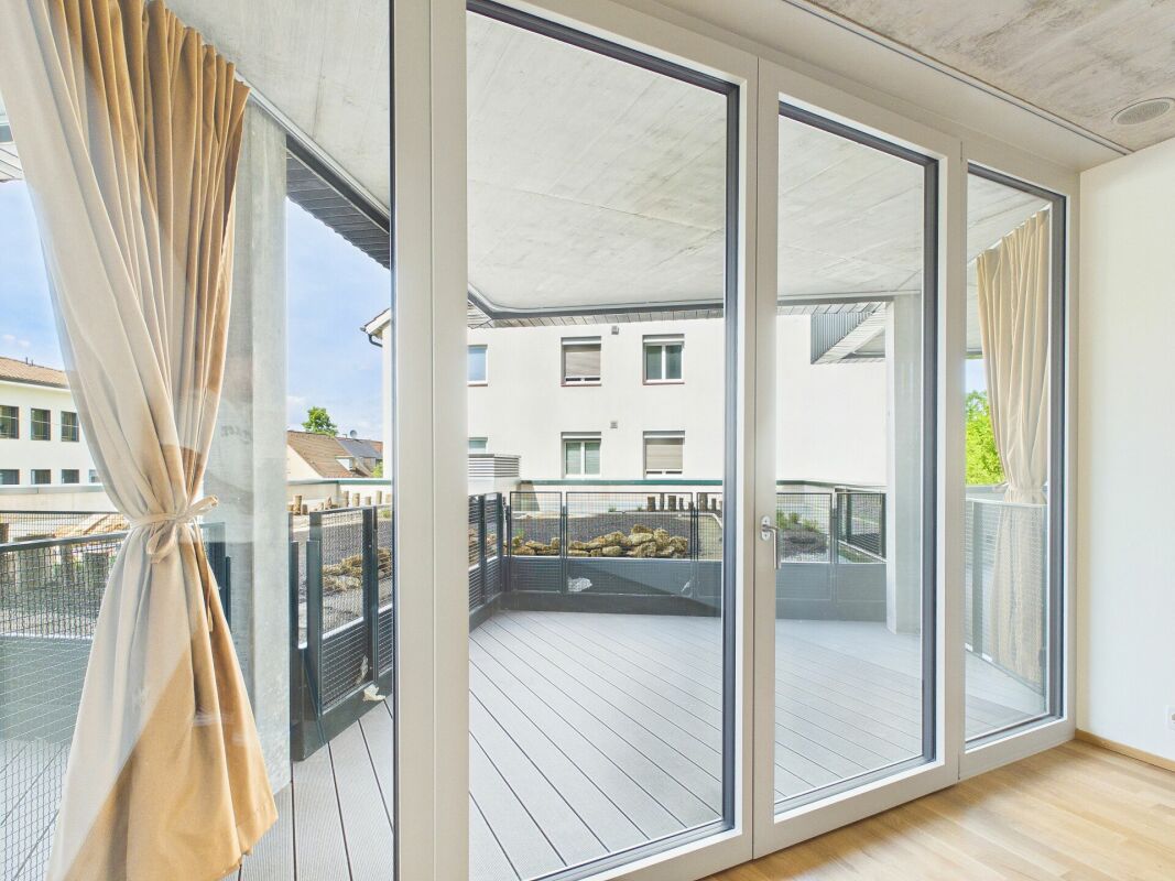 Heller Wohnraum mit großer Fensterfront zum Balkon