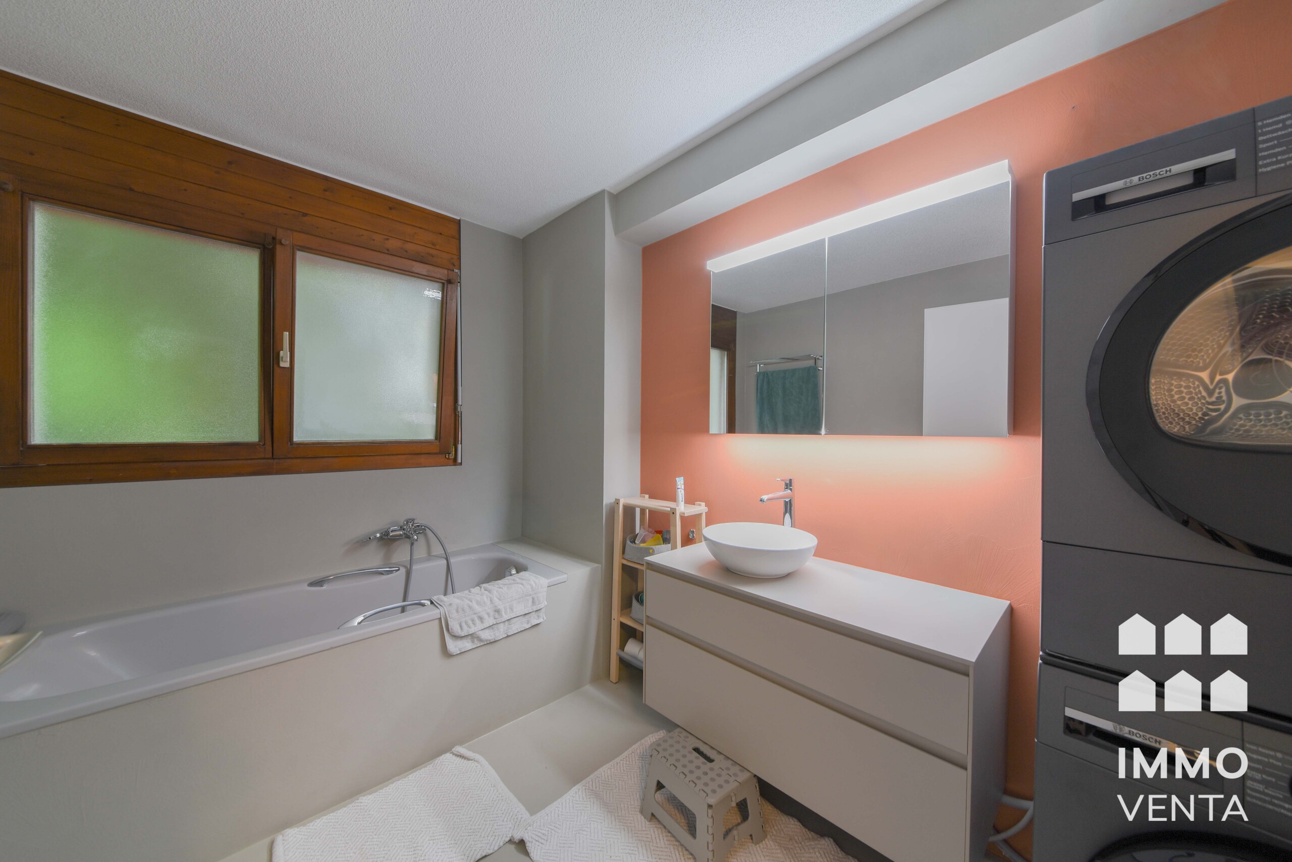 Modernes Badezimmer mit Waschmaschine und Wannenbad