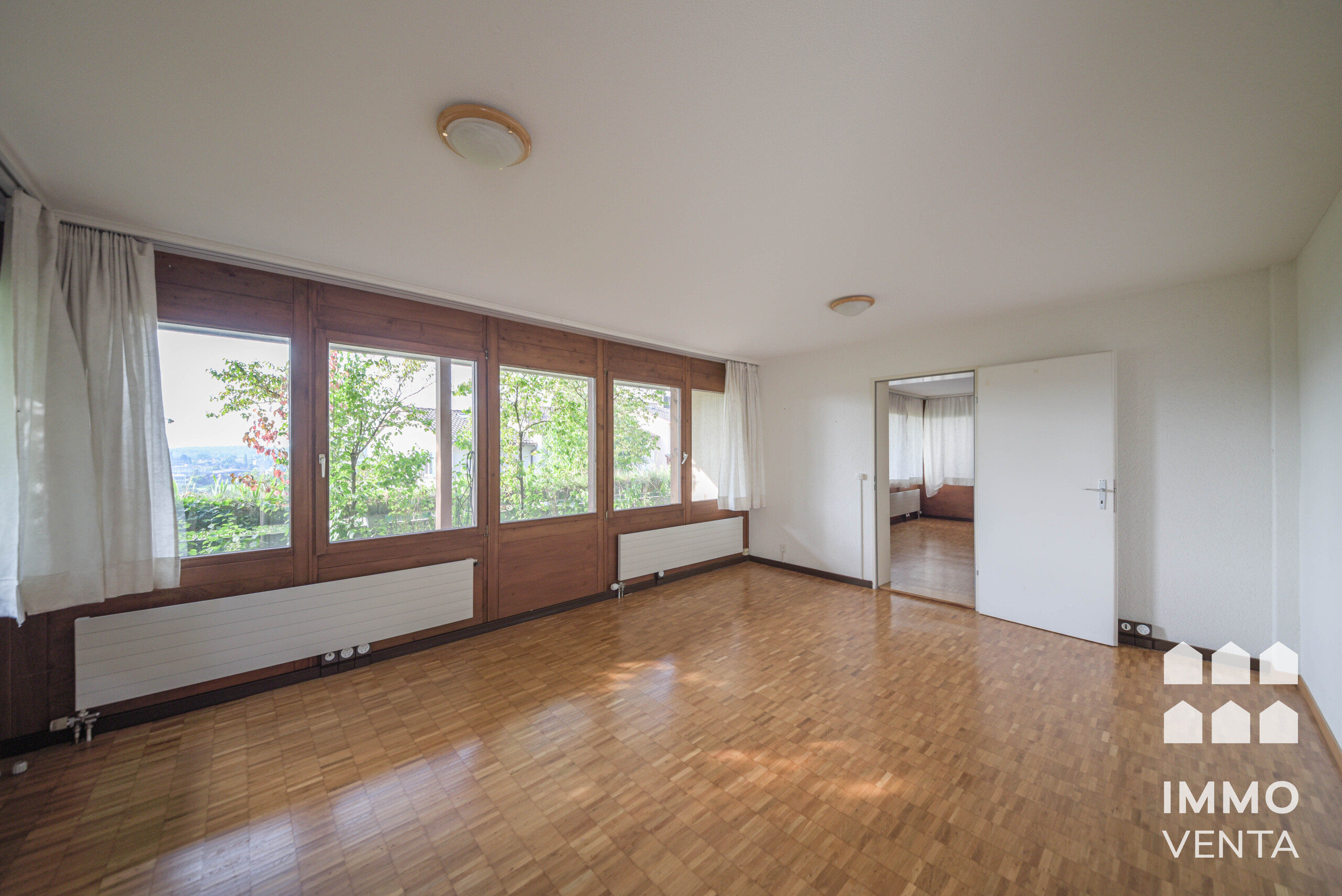 Heller leerer Wohnraum mit großen Holzfenstern