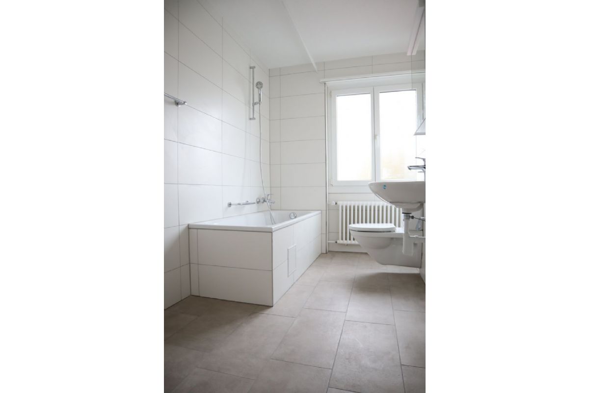 Helles Badezimmer mit Badewanne und Fenster