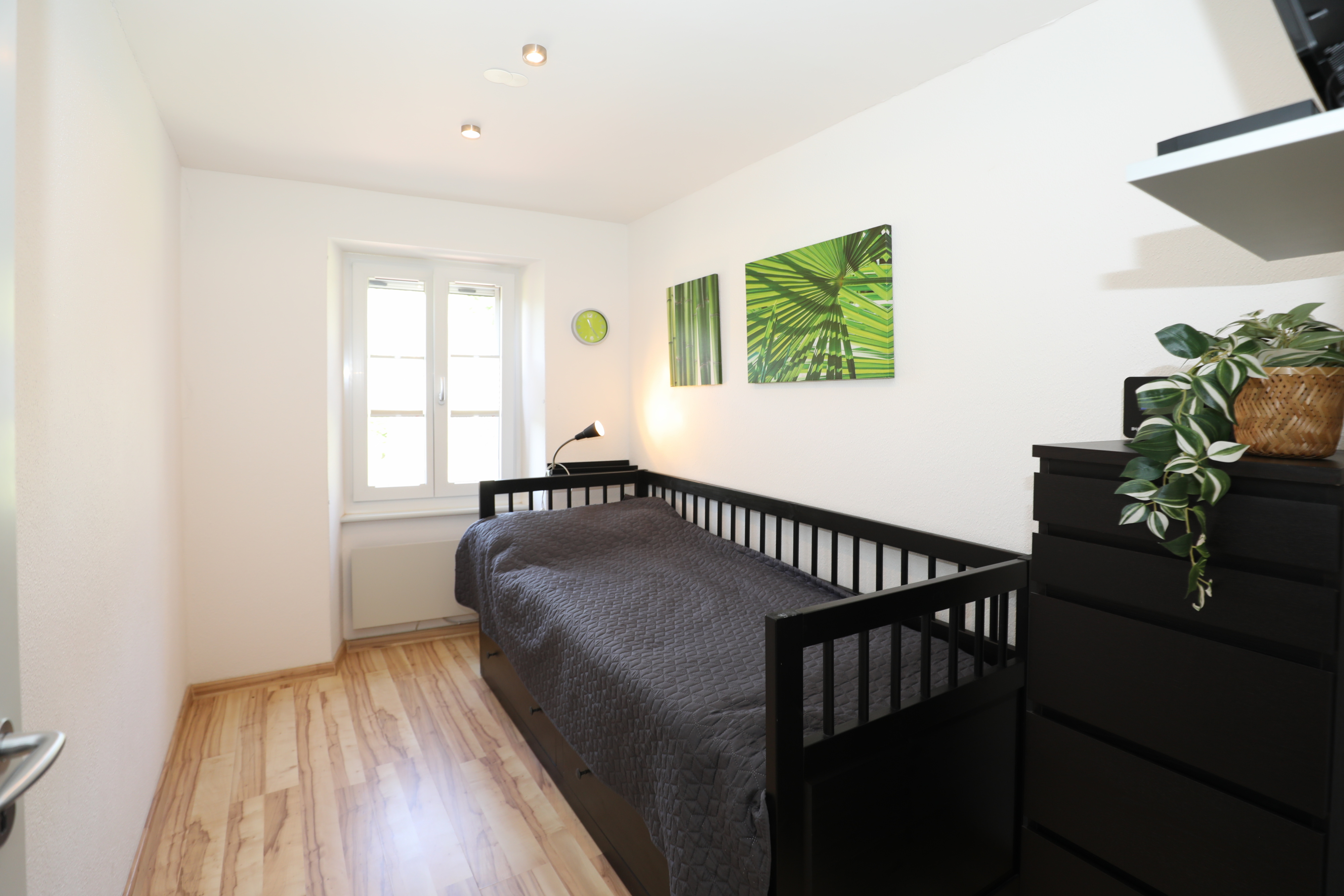 Helles Schlafzimmer mit Einzelbett und Holzoptik-Boden