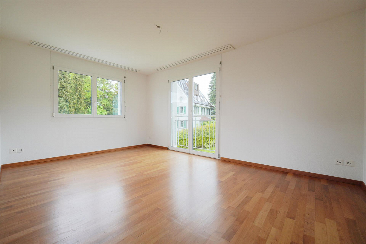 Heller leerer Wohnraum mit Holzfußboden und Balkonfenstern