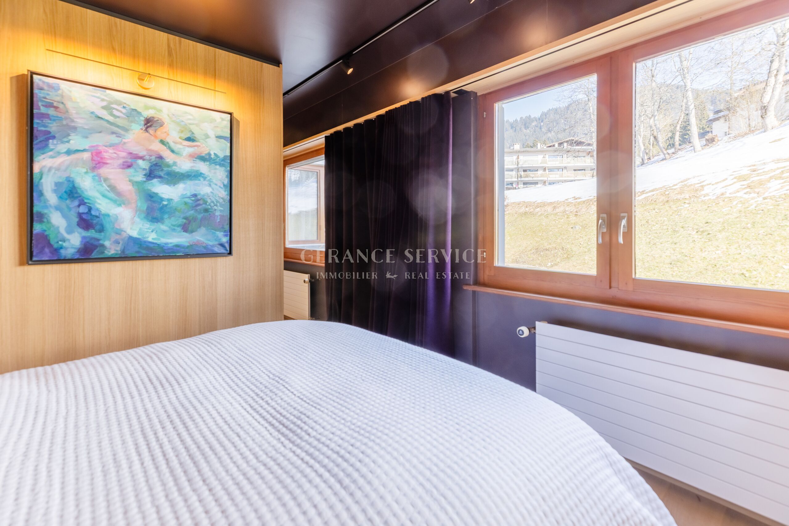 Helles Schlafzimmer mit Holzoptik und Bergblick