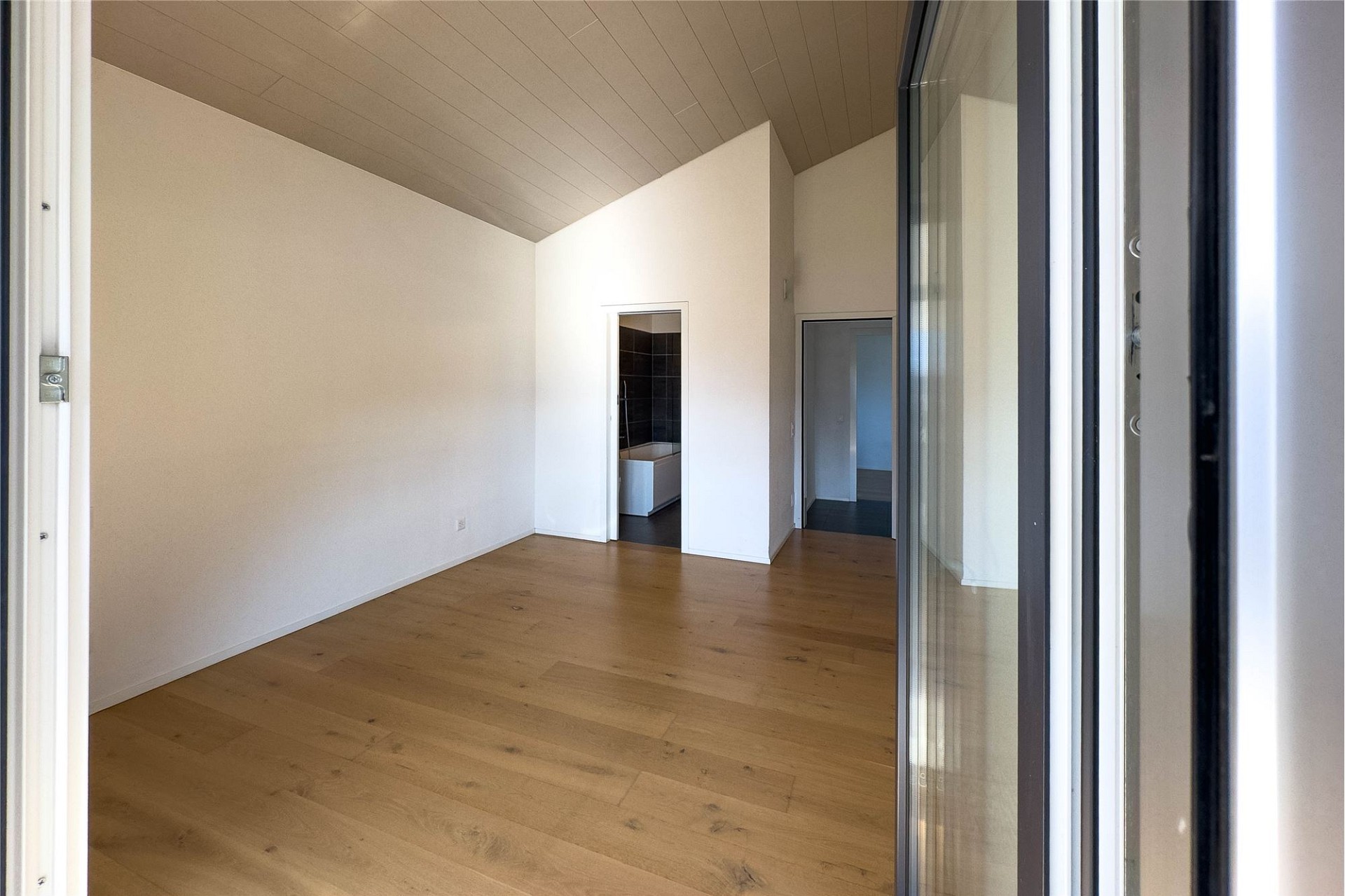 Heller, leerer Innenraum mit Holzfußboden und hohen Wänden