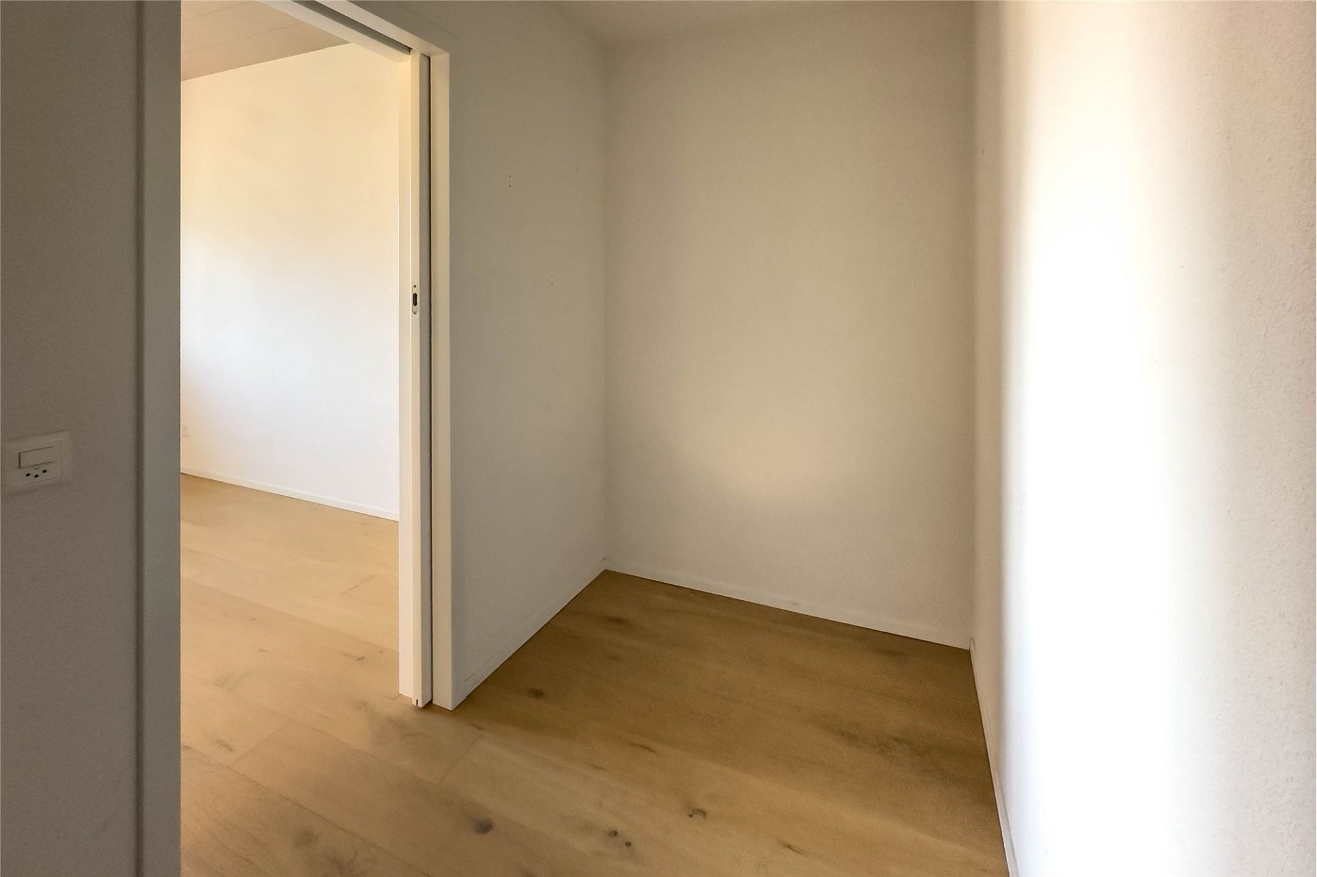 Heller leerer Raum mit Holzboden und offener Tür