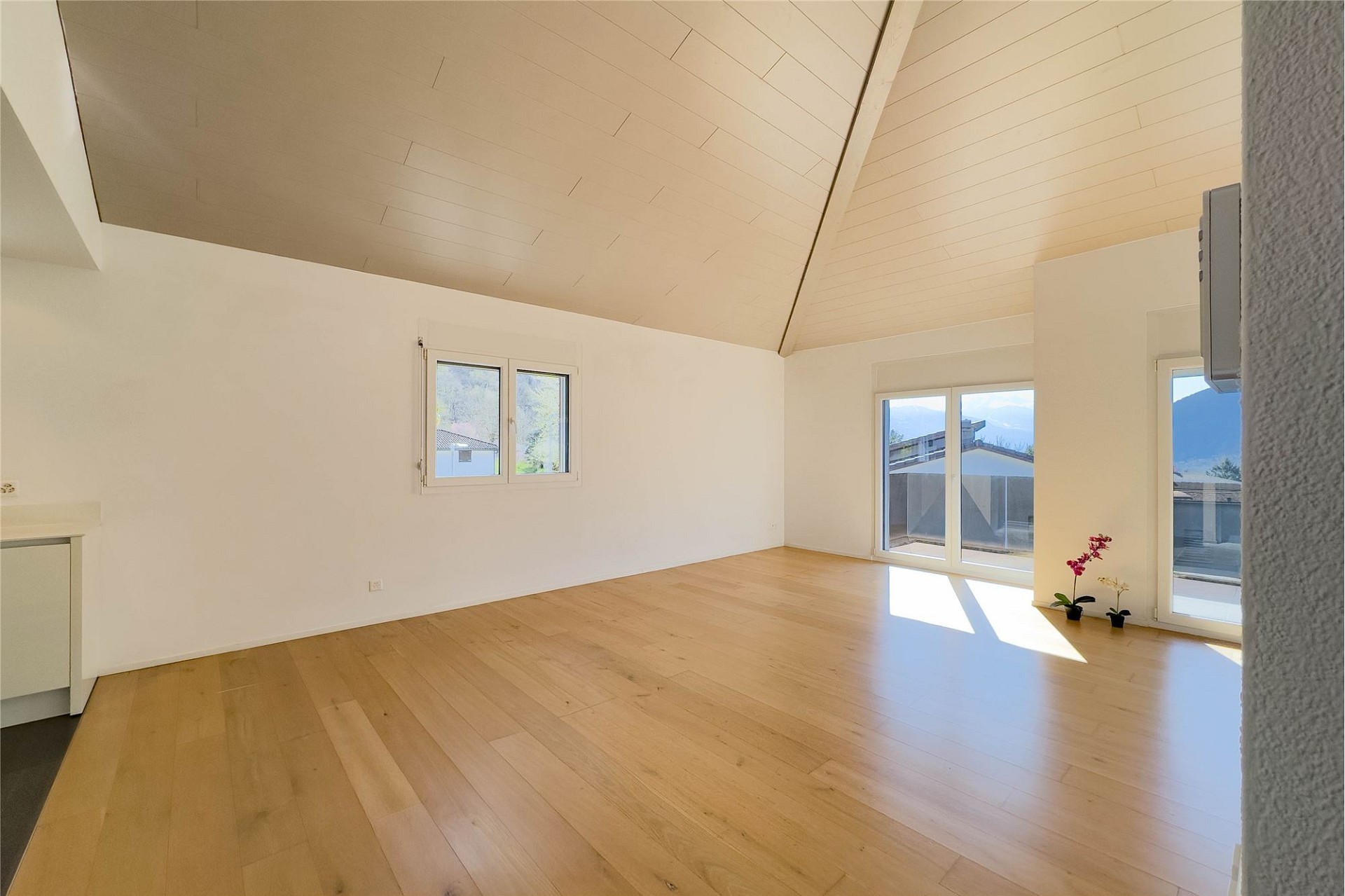 Helles Dachgeschosszimmer mit Holzdecke und Blick ins Grüne