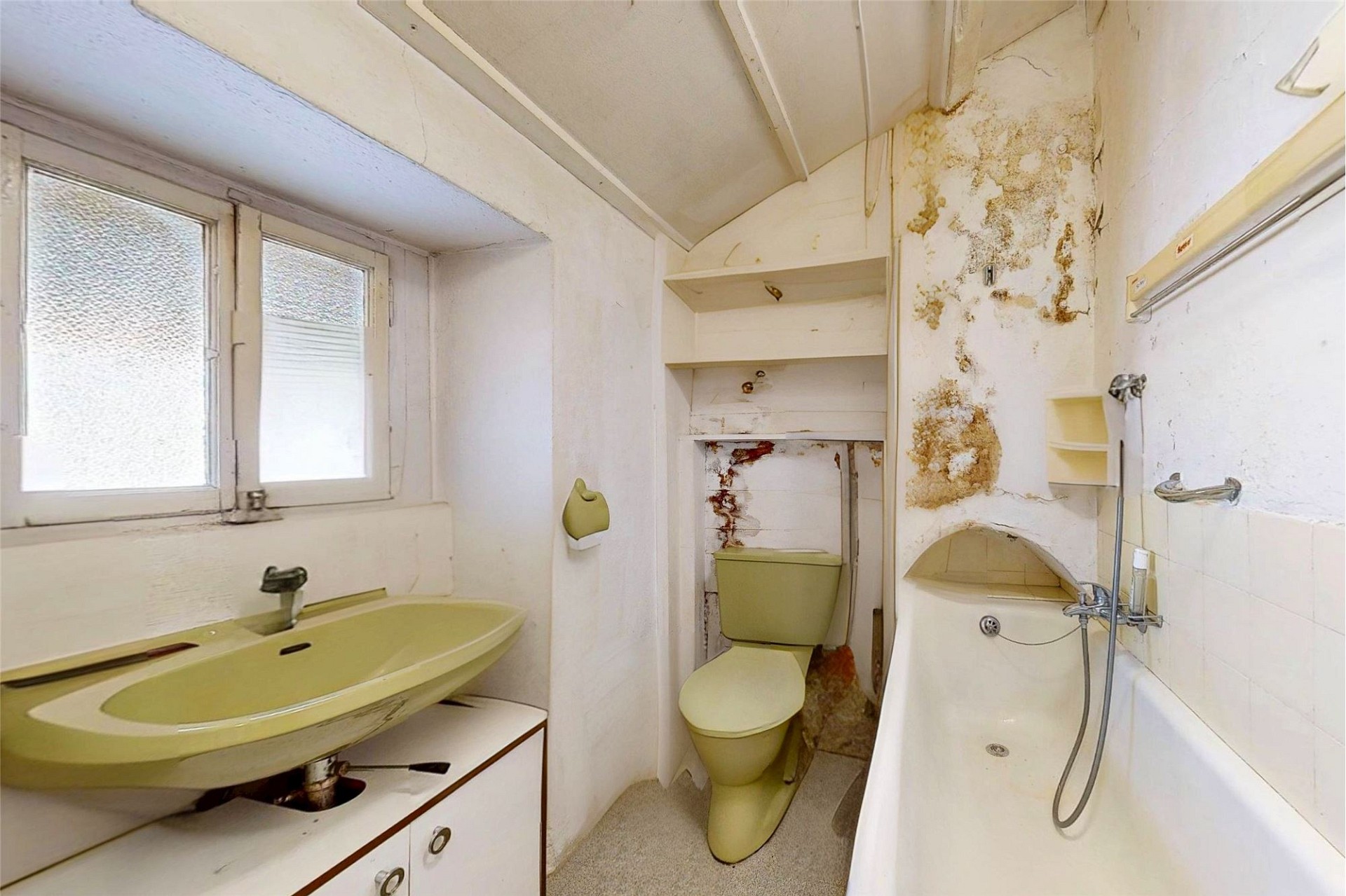 Veraltetes, renovierungsbedürftiges Badezimmer mit sichtbaren Feuchtigkeitsschäden