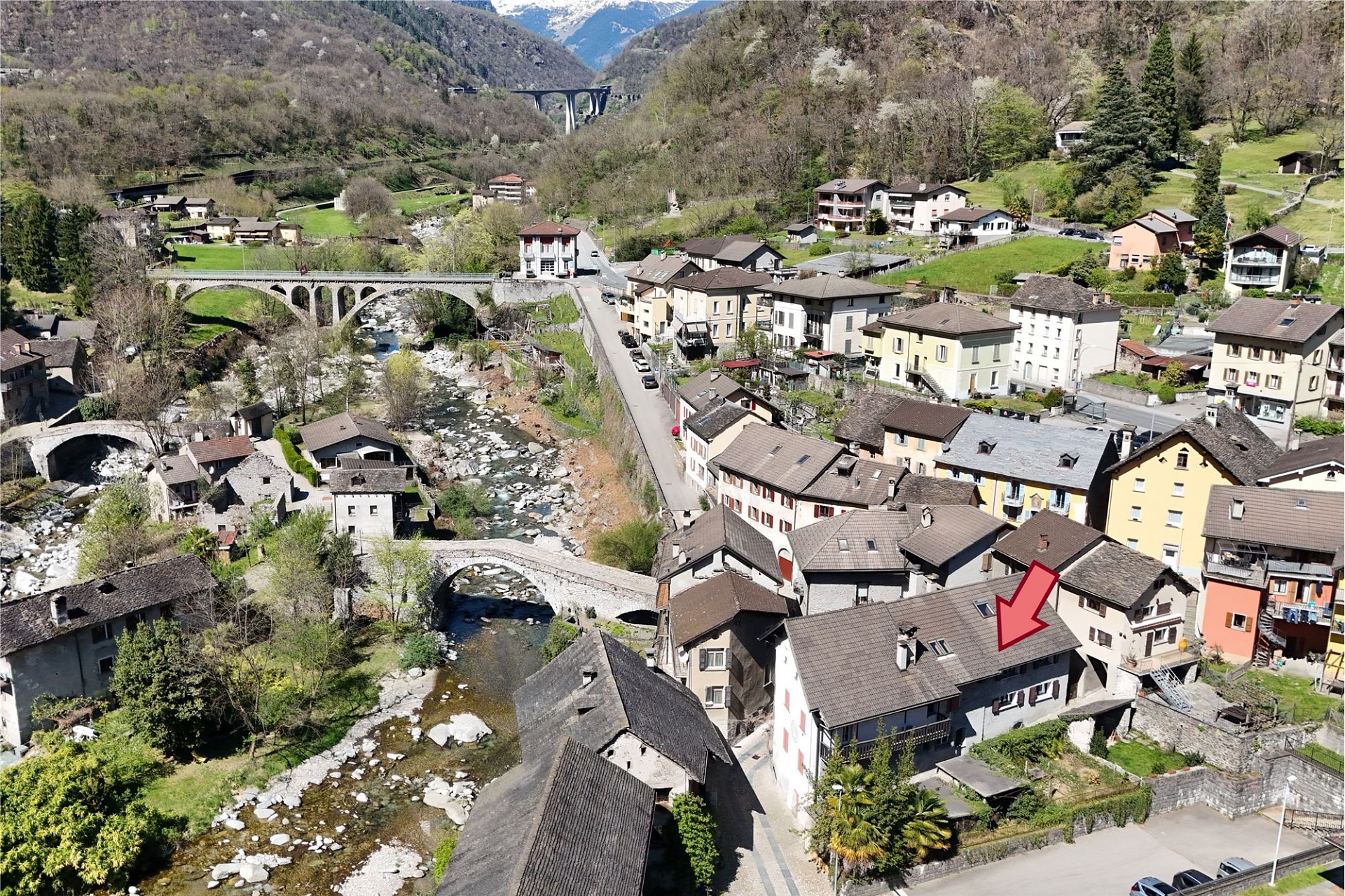 Luftaufnahme eines Alpenortes mit Fluss, Brücken und Wohnhäusern