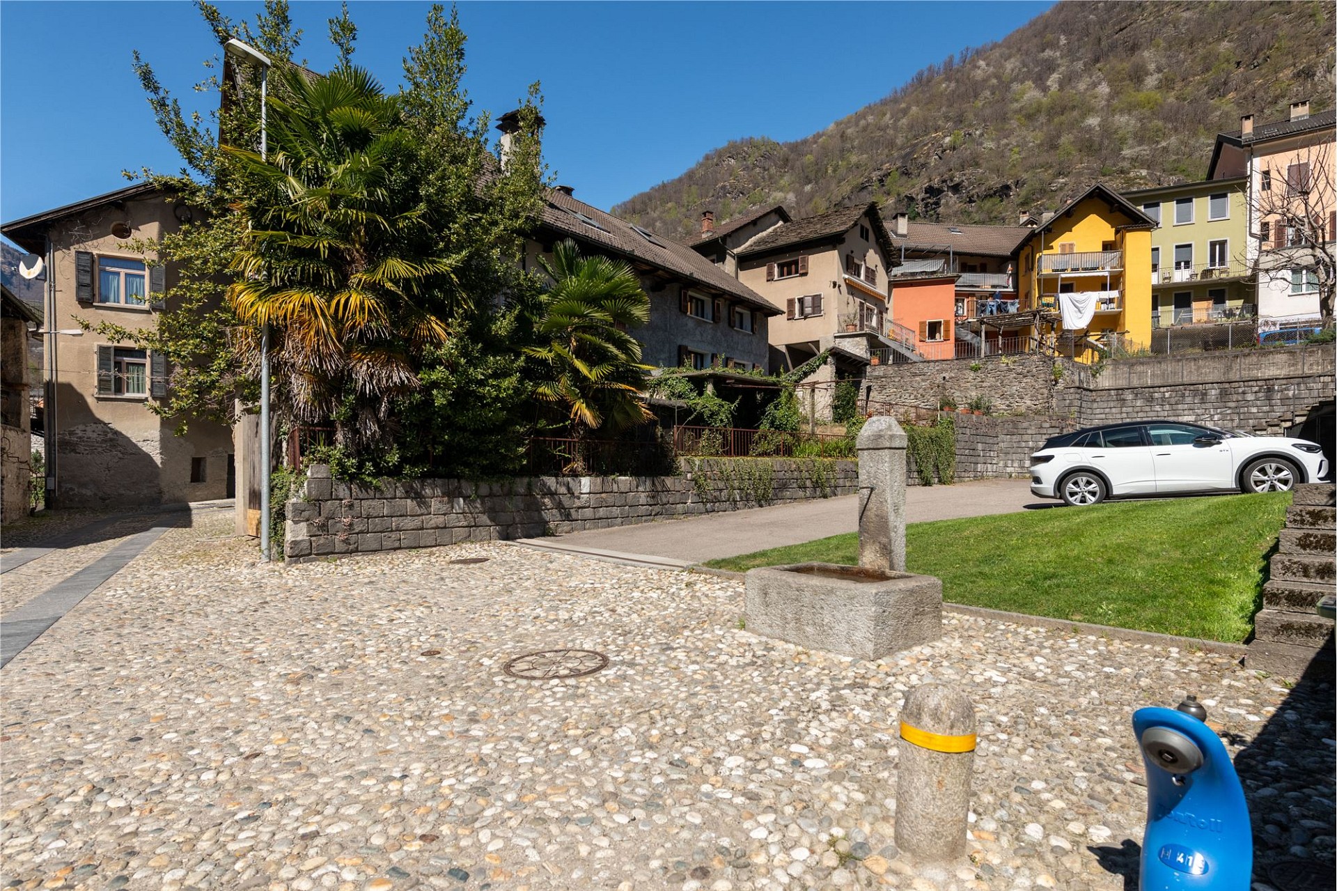 Dorfstraße mit mediterran wirkenden Häusern und Bergkulisse