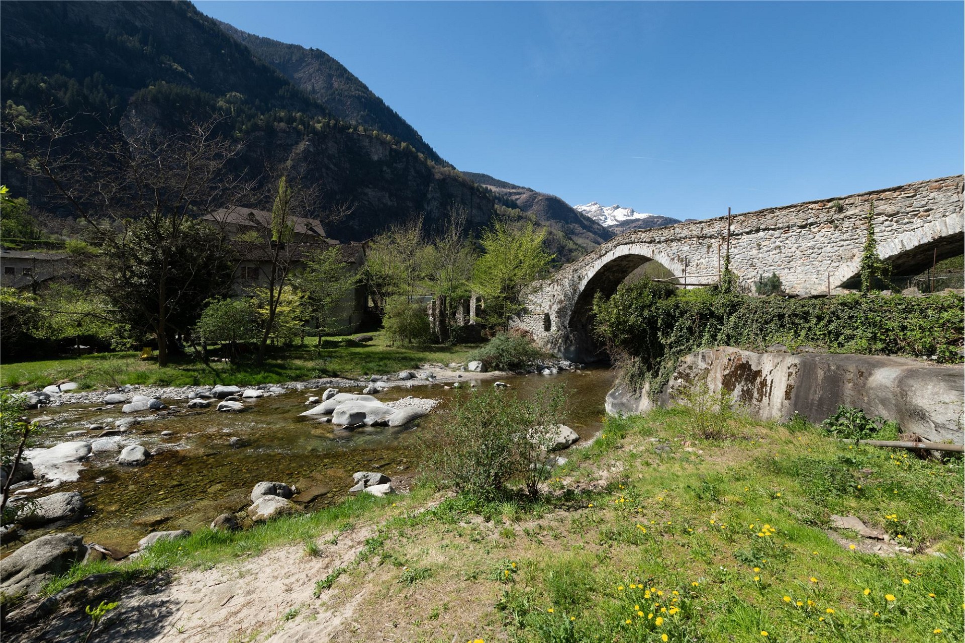 Alte Steinbrücke über einen Fluss in alpiner Landschaft