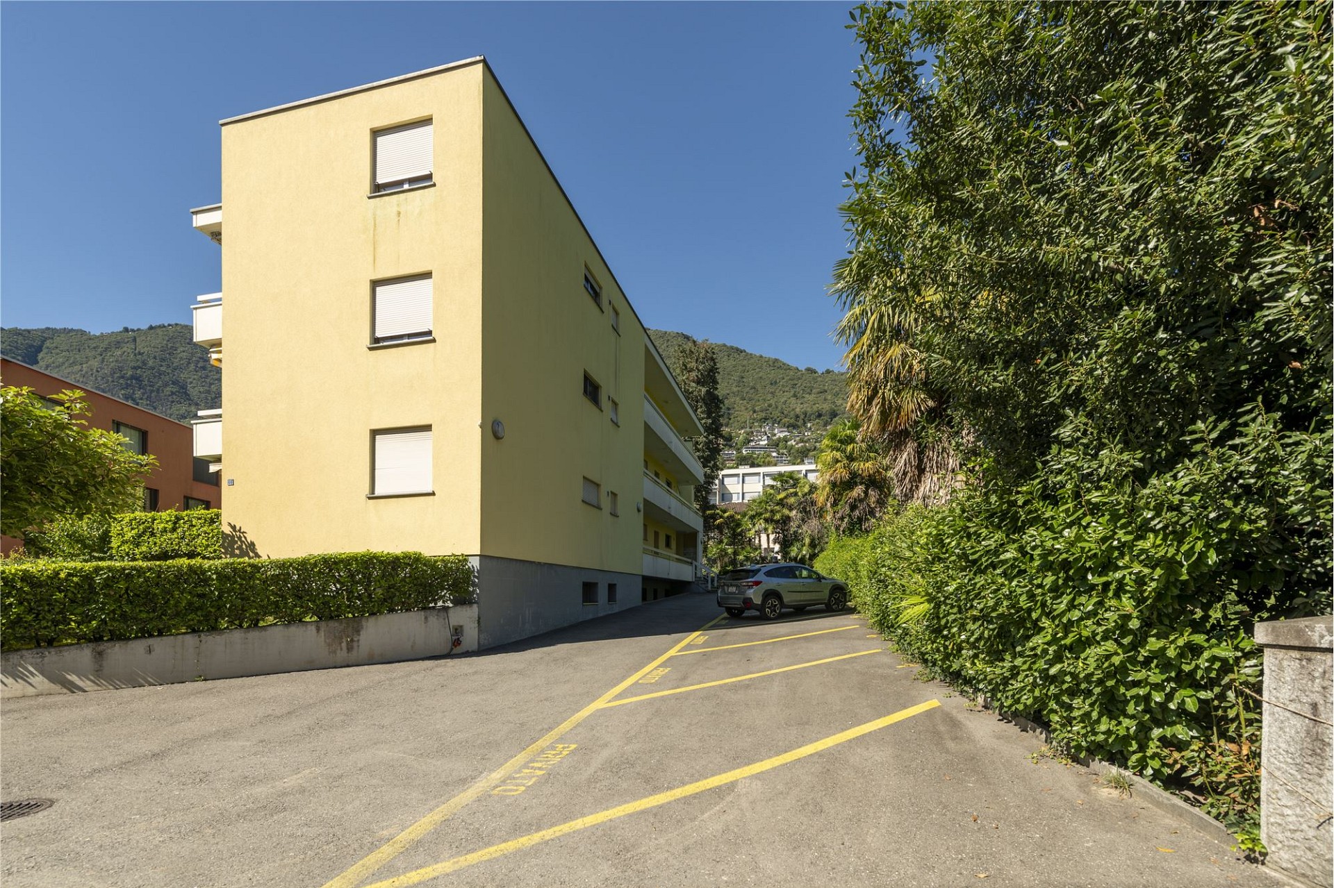 Mehrfamilienhaus mit Zufahrt und Vegetation