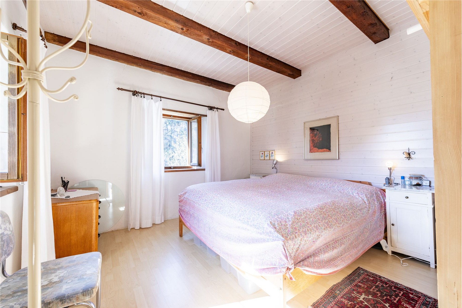 Helles Schlafzimmer im Dachgeschoss mit sichtbaren Holzbalken