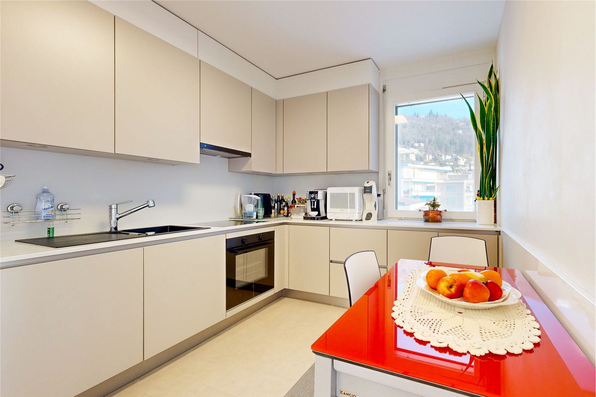 Helle, moderne Einbauküche mit Fenster und roter Tischplatte