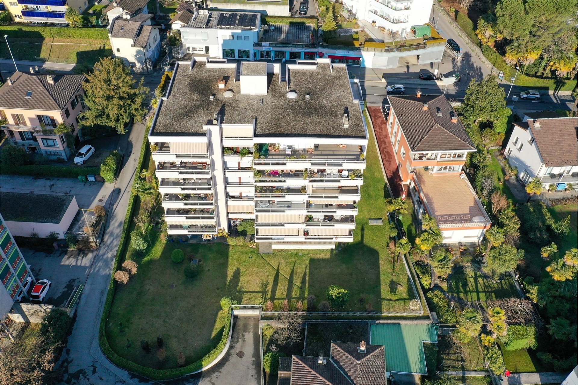 Luftaufnahme eines Mehrfamilienhauses mit Gärten
