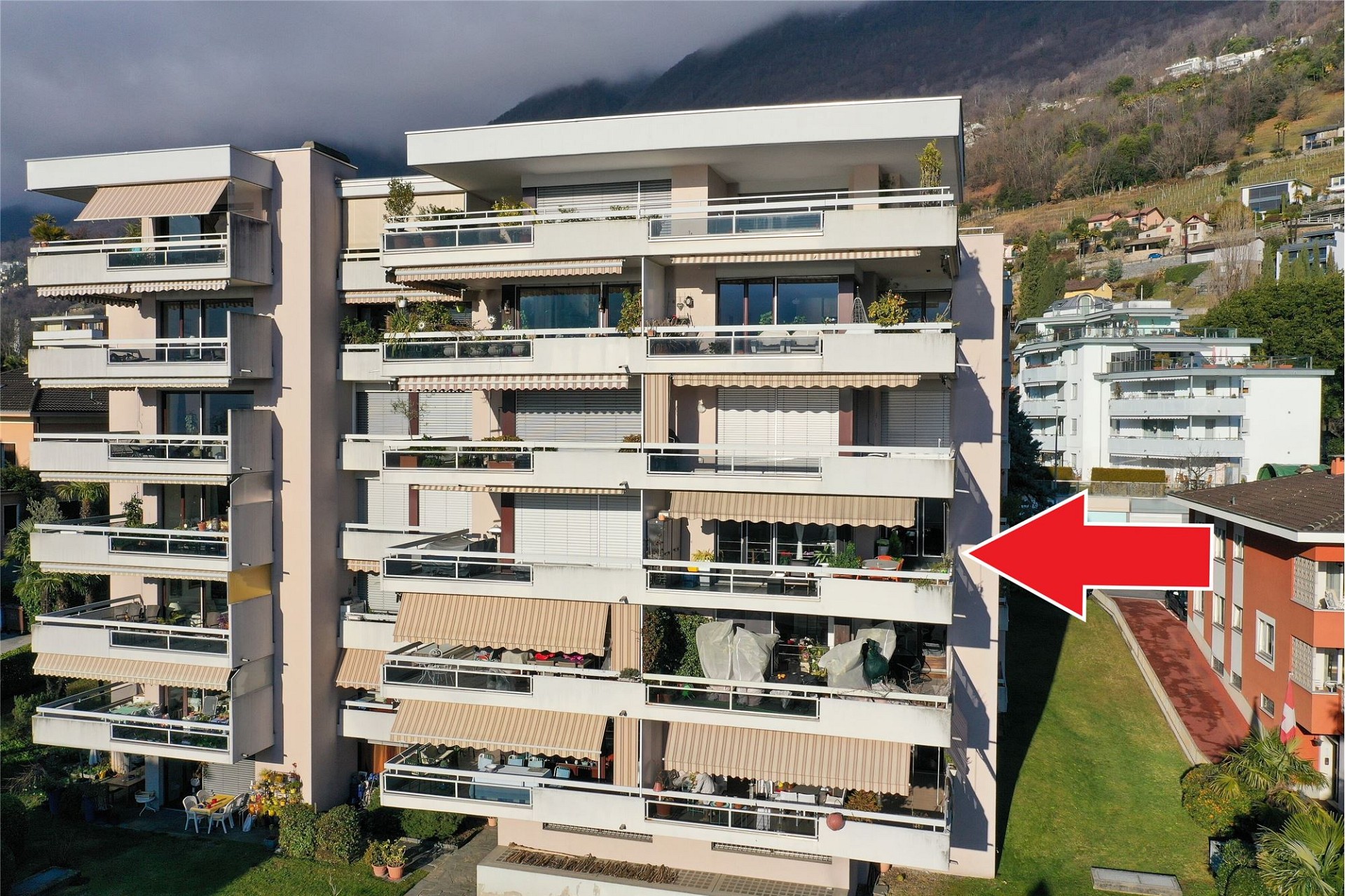 Mehrfamilienhaus mit großen Balkonen und Bergkulisse