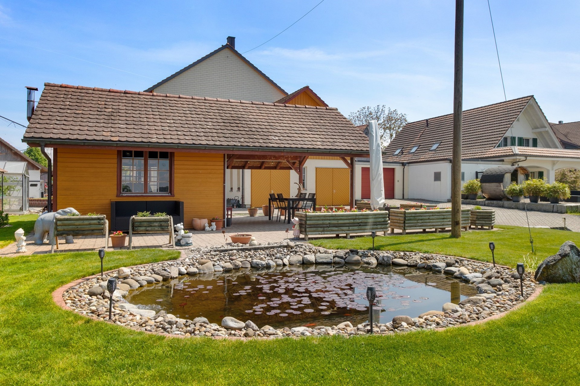 Gepflegter Garten mit Teich und Nebengebäuden