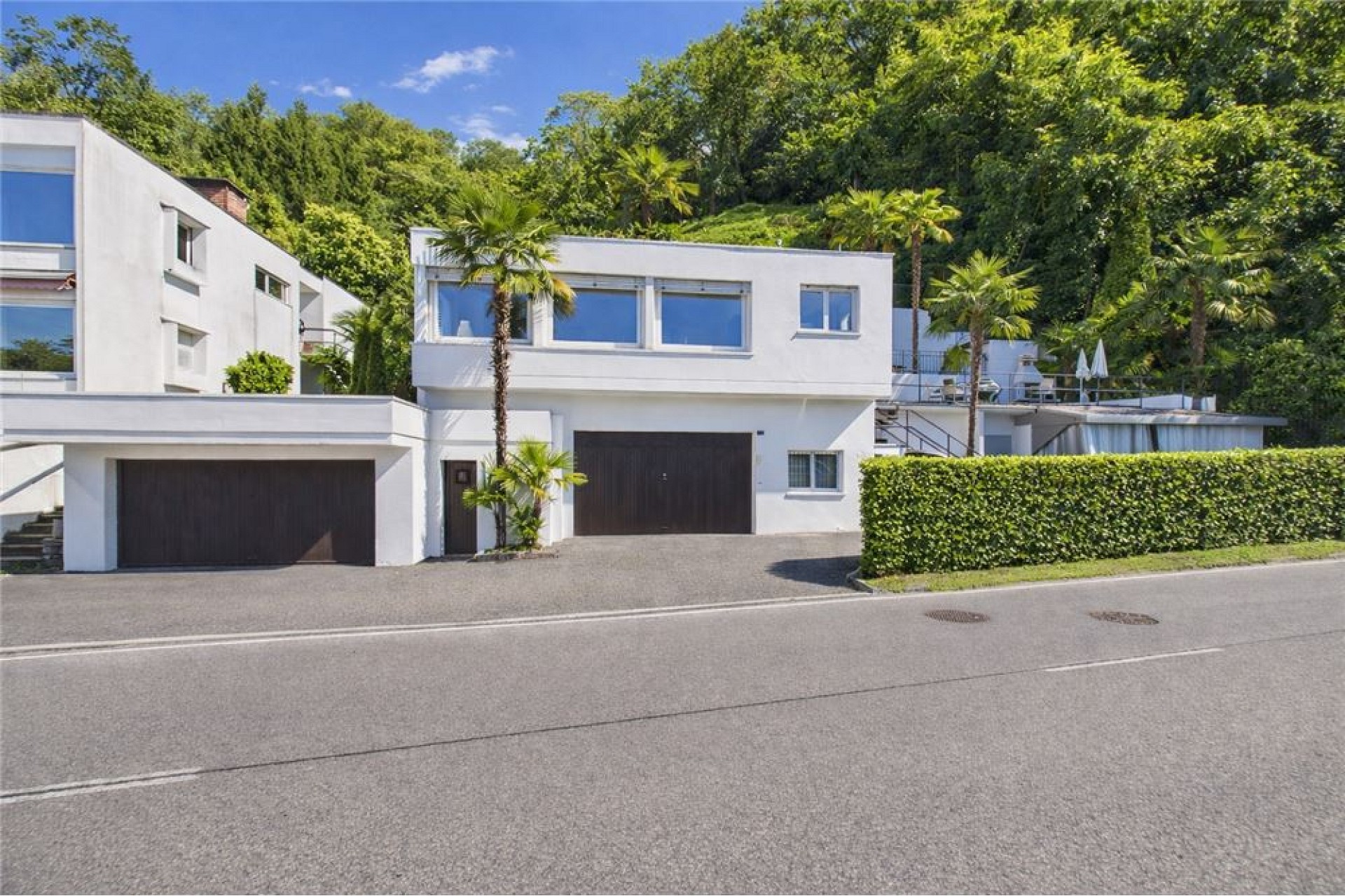 Modernes weißes Wohnhaus mit Garagen und tropischer Umgebung