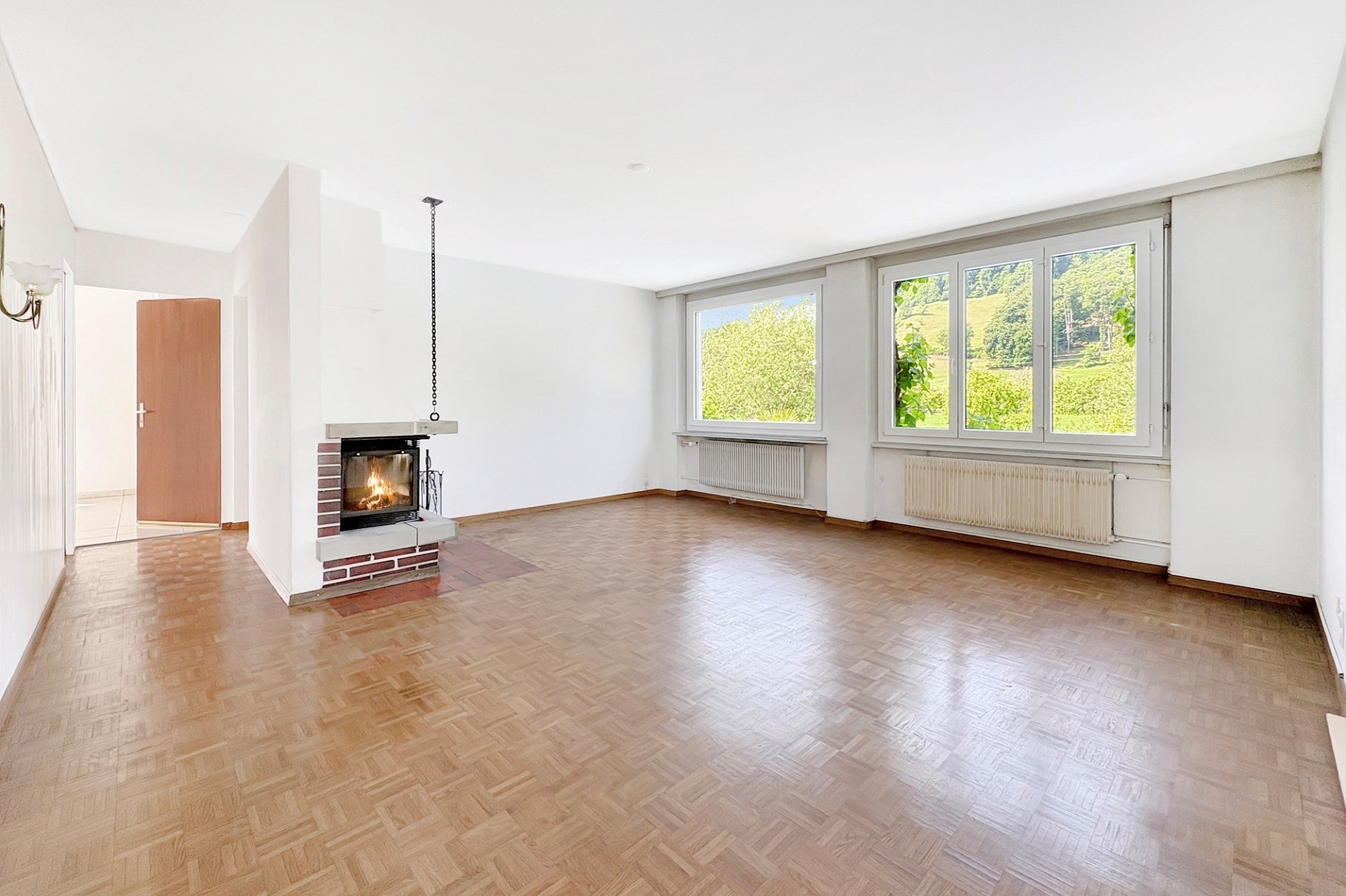 Heller Wohnraum mit Kamin und Blick ins Grüne