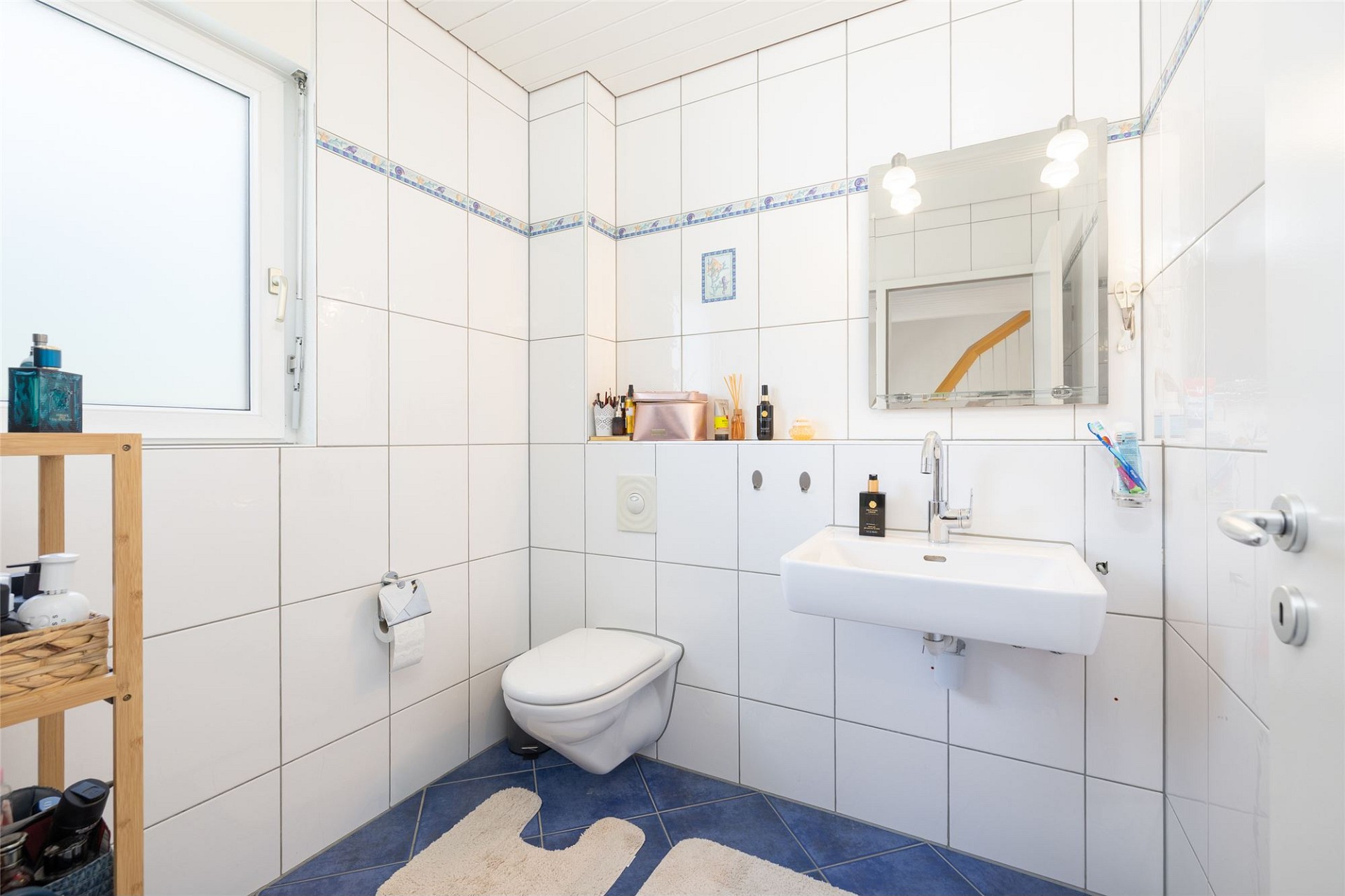 Kleines Gäste-WC mit weißer Fliesenverkleidung und blauem Boden