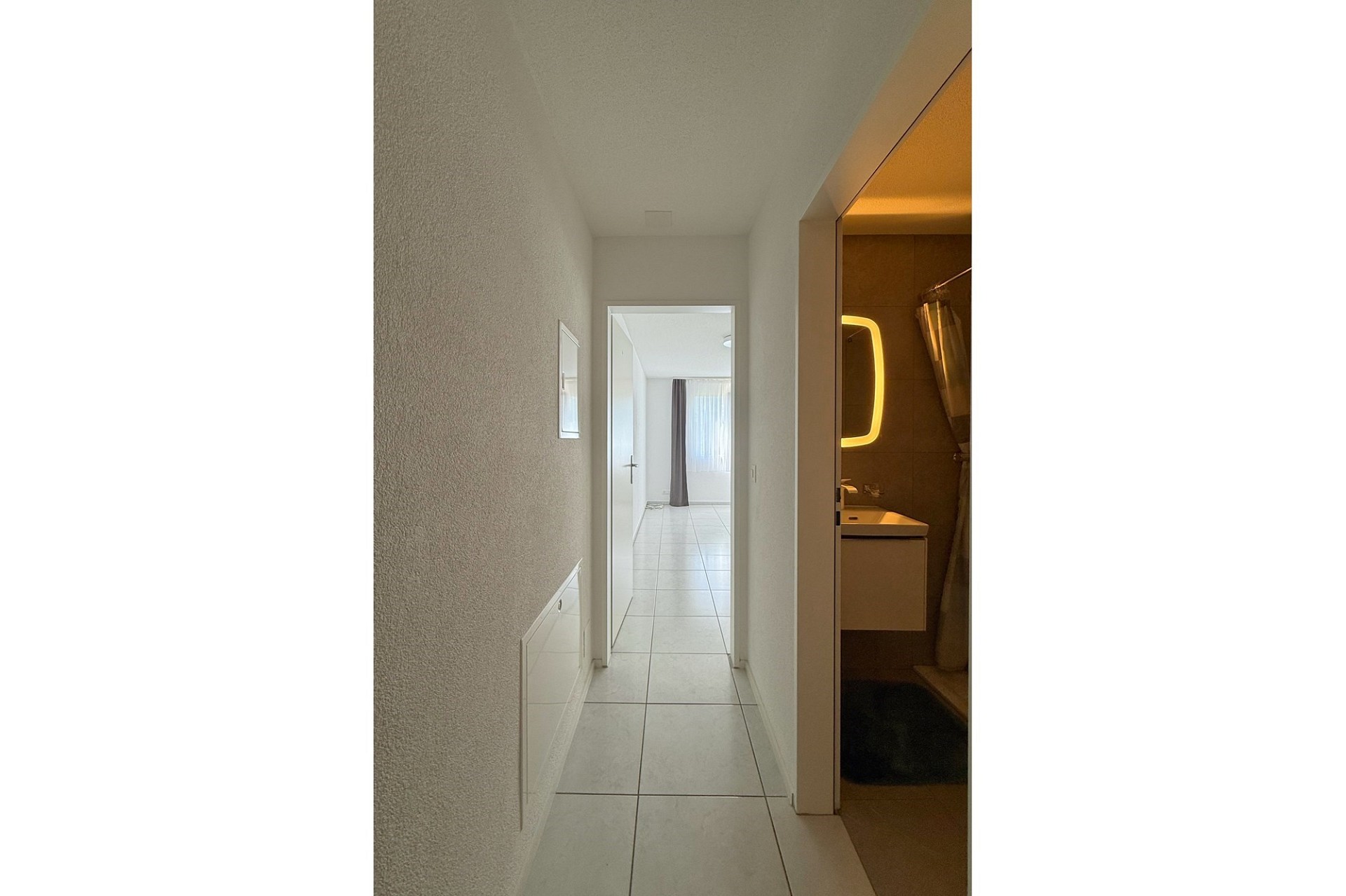 Heller Flur mit Blick ins Zimmer und ins Bad