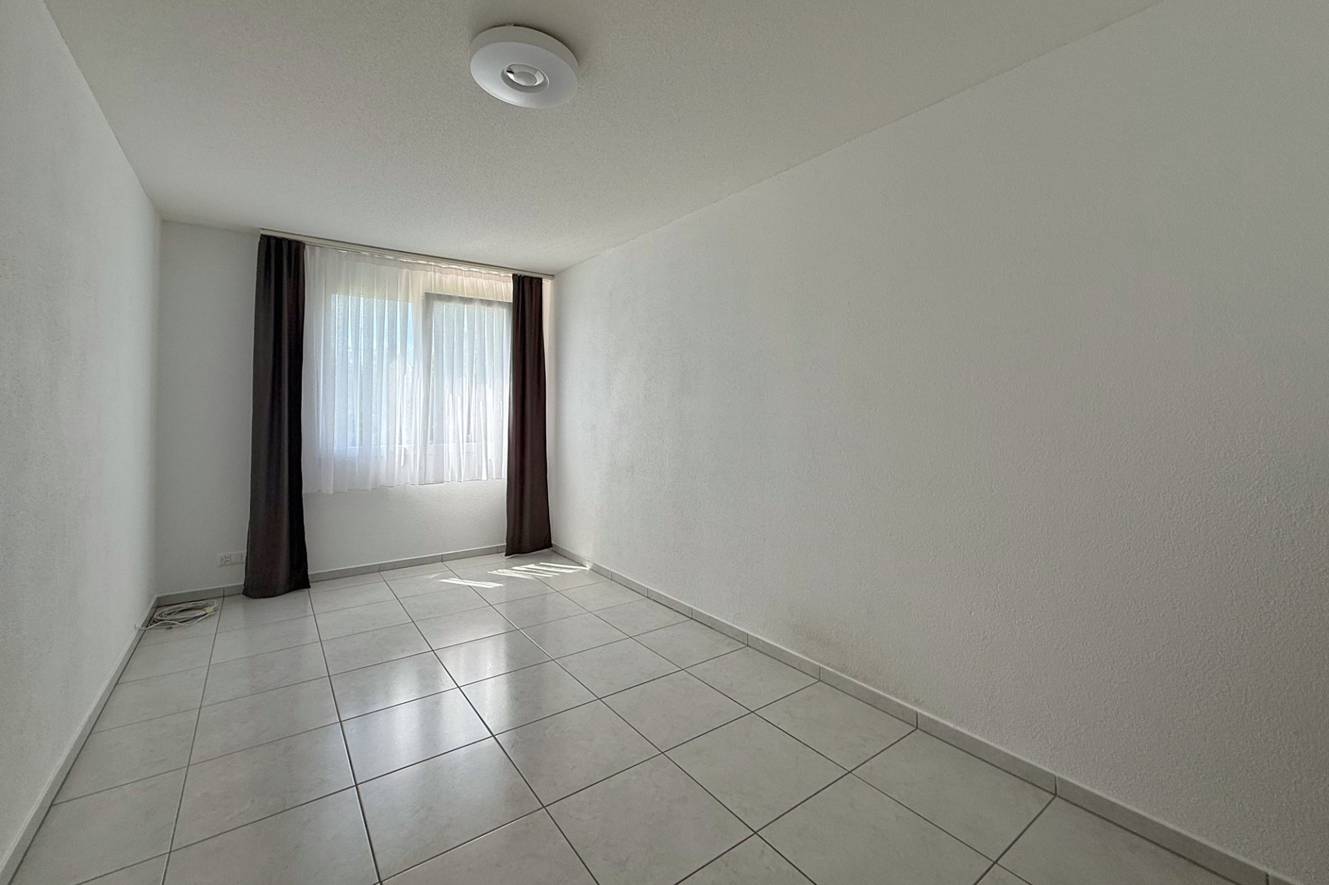 Leerer heller Raum mit Fliesenboden und Fenster