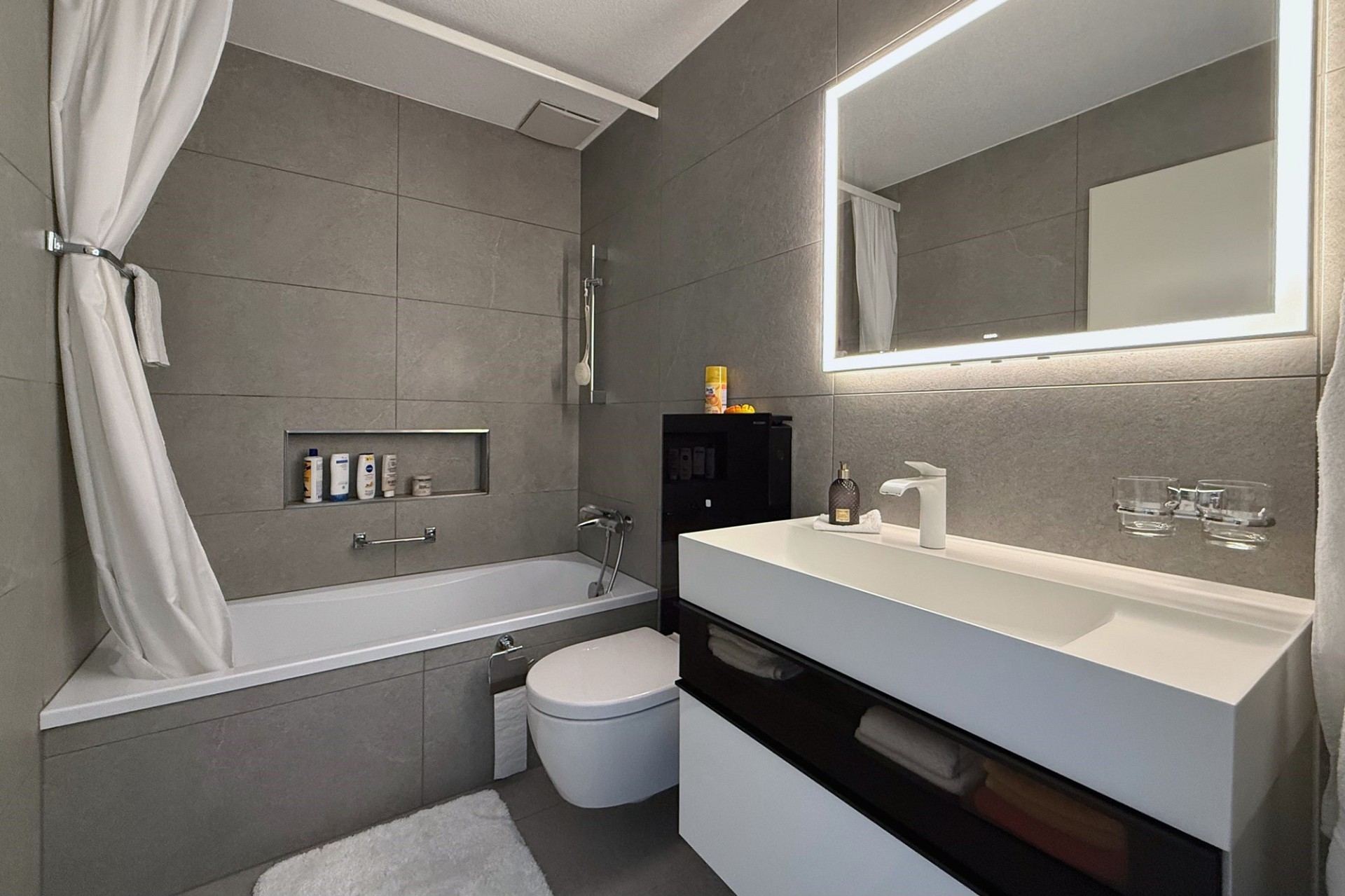 Modernes Badezimmer mit Badewanne und beleuchtetem Spiegel