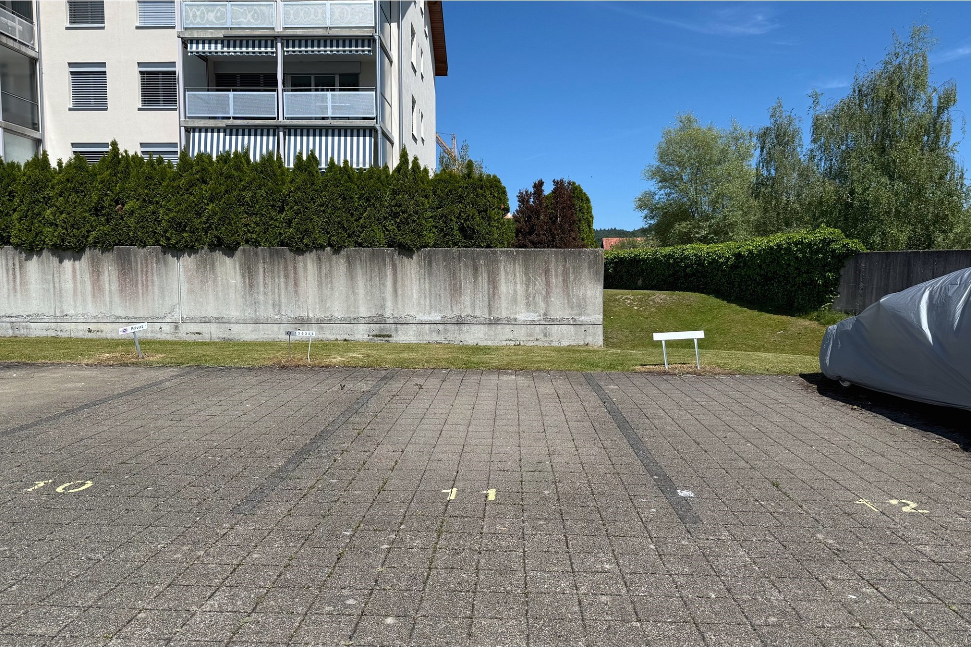Außenansicht eines Wohngebäudes mit Parkplatz und Grünfläche