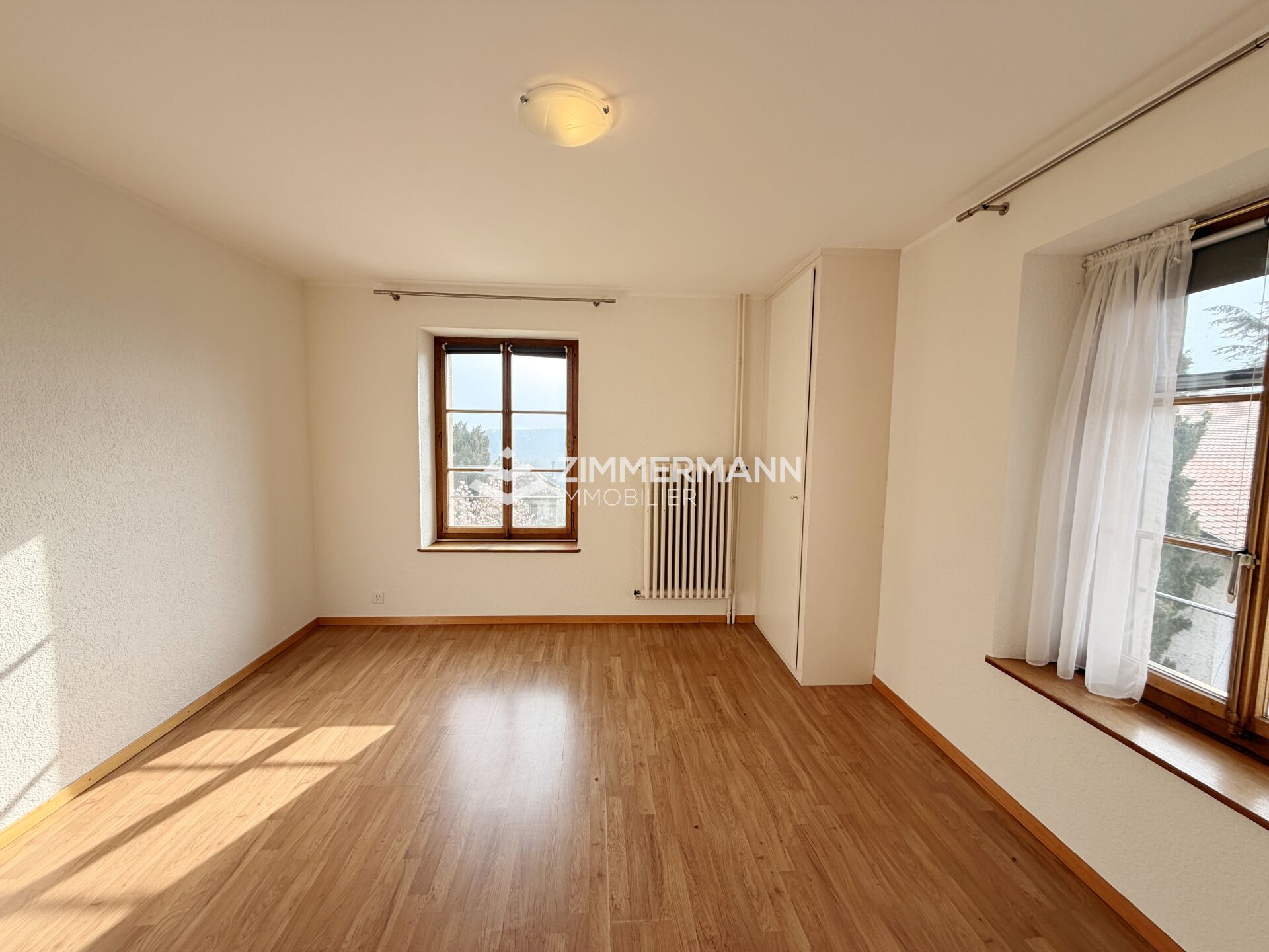 Heller leerer Raum mit Holzfußboden und Fenstern