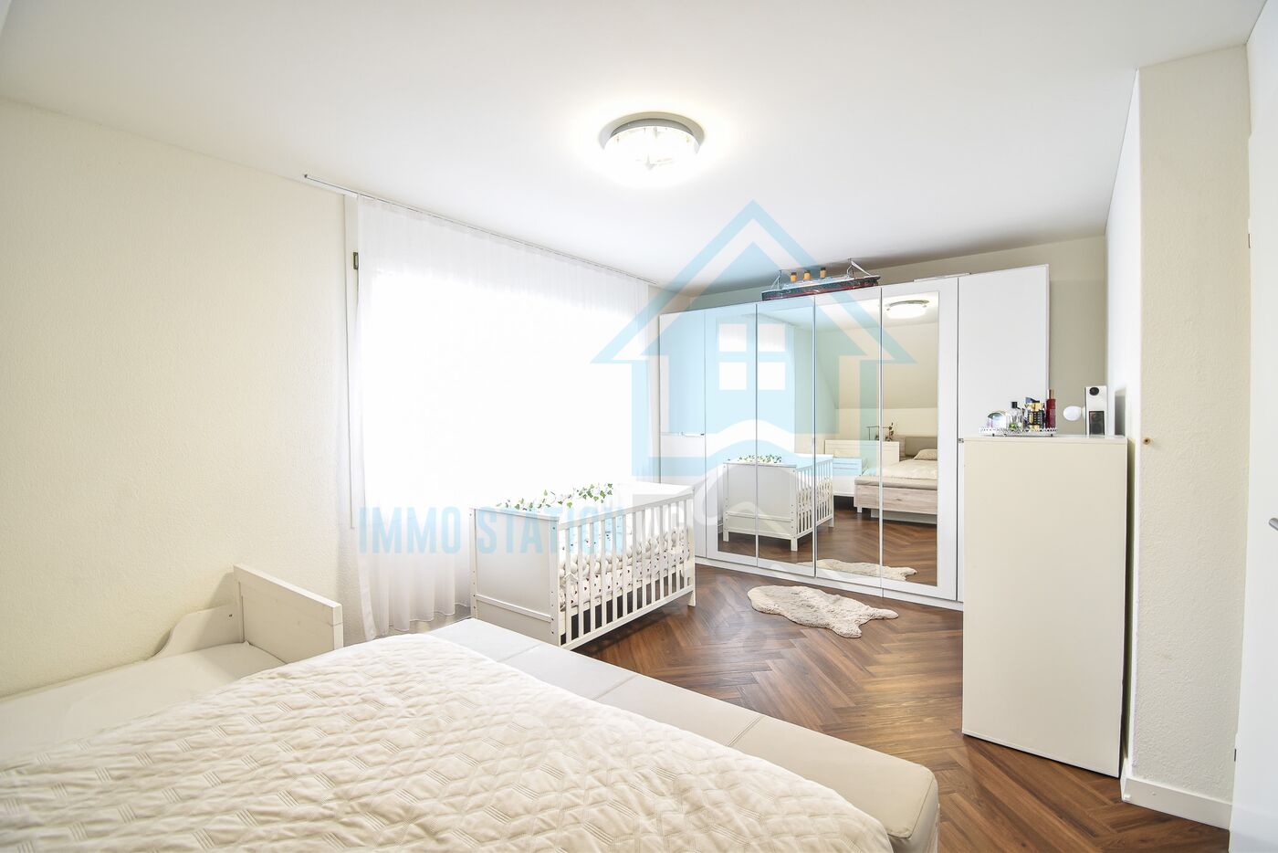 Helles Schlafzimmer mit Babybett und Spiegelkleiderschrank