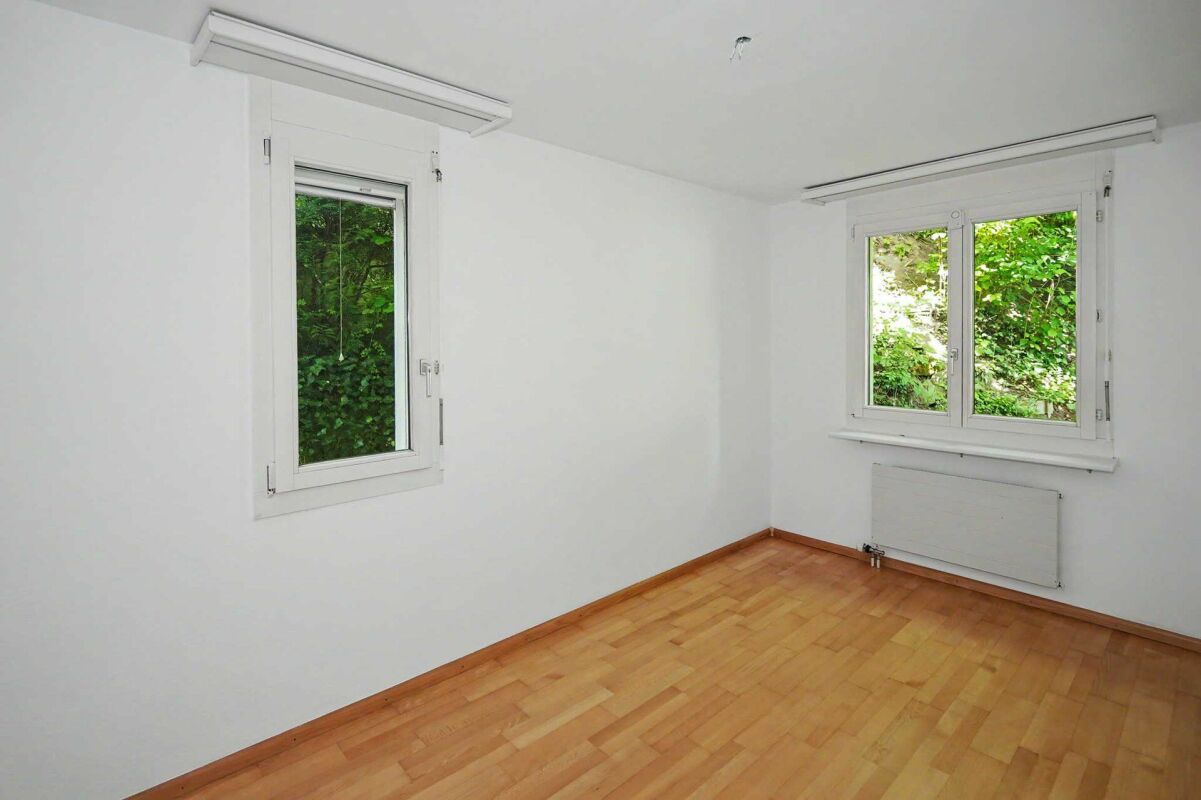 Leerer heller Raum mit zwei Fenstern und Holzparkett