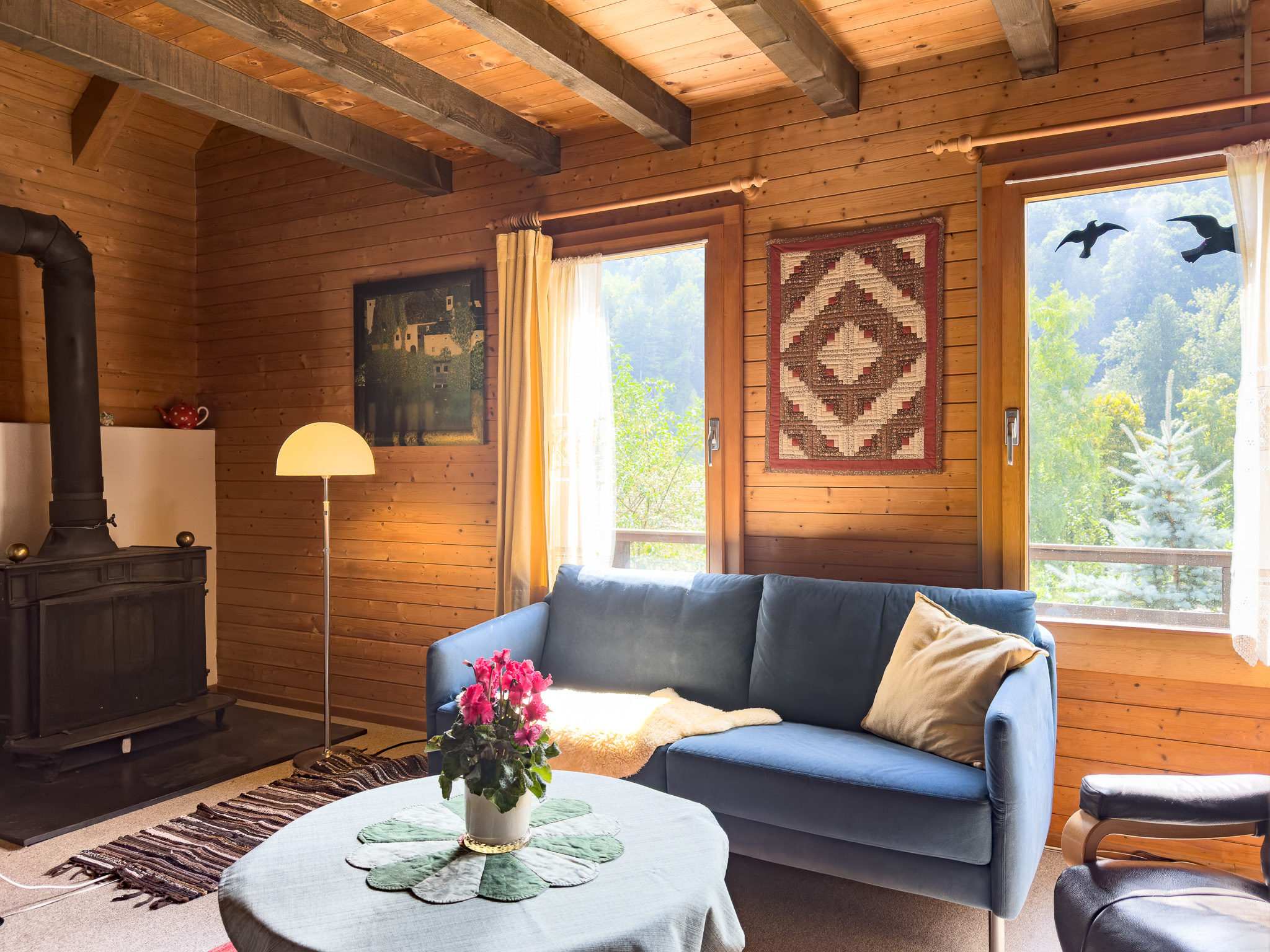 Gemütliches Holzwohnzimmer mit Kaminofen und Blick ins Grüne