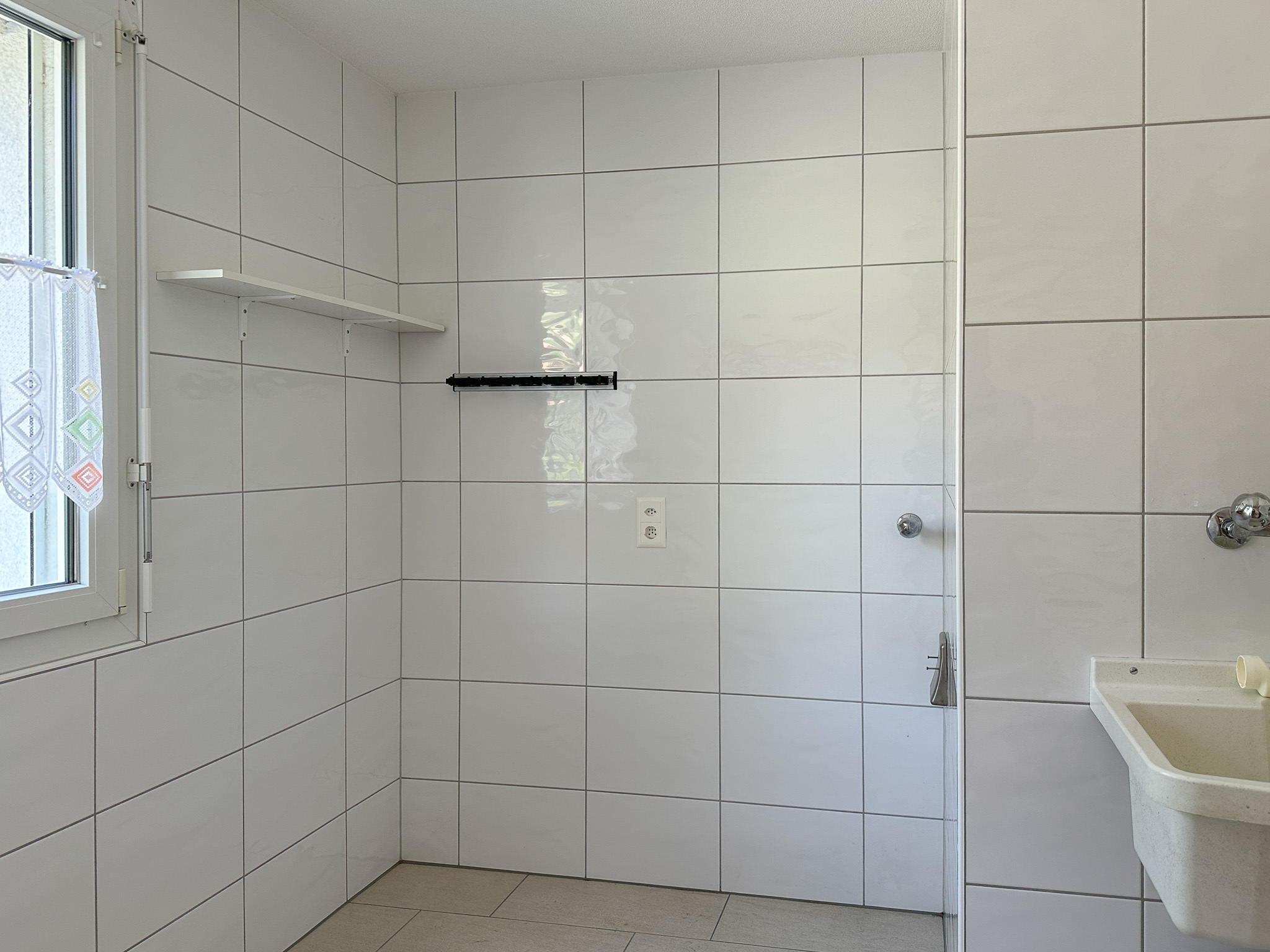 Heller Nassraum mit weißen Wandfliesen