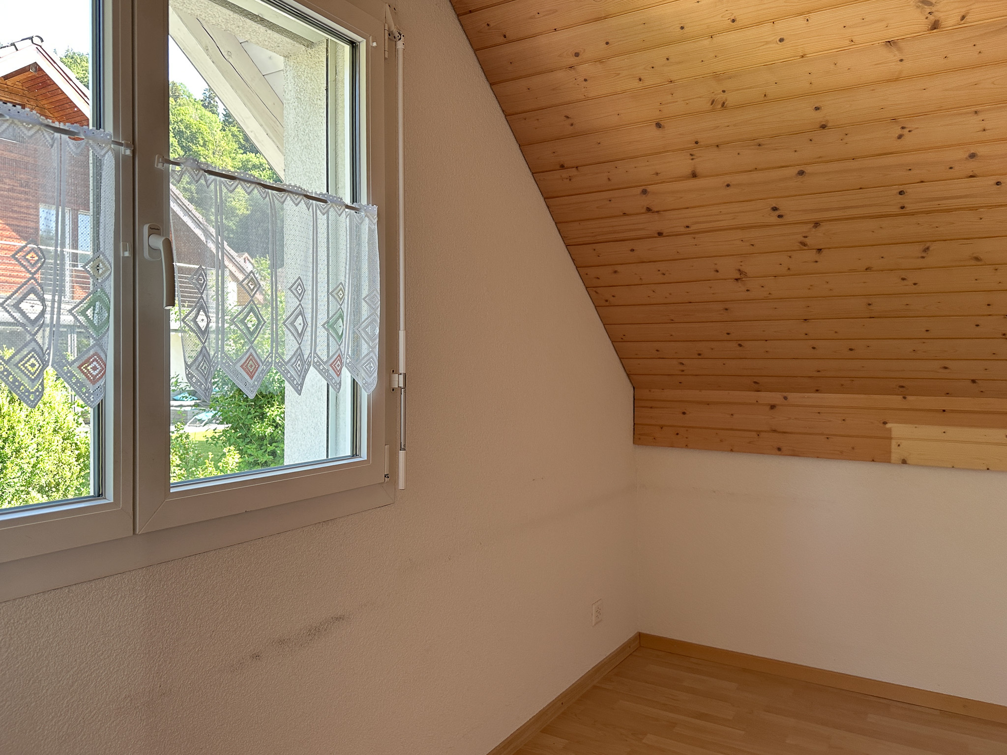 Helles Dachzimmer mit Fenster und Holzdecke