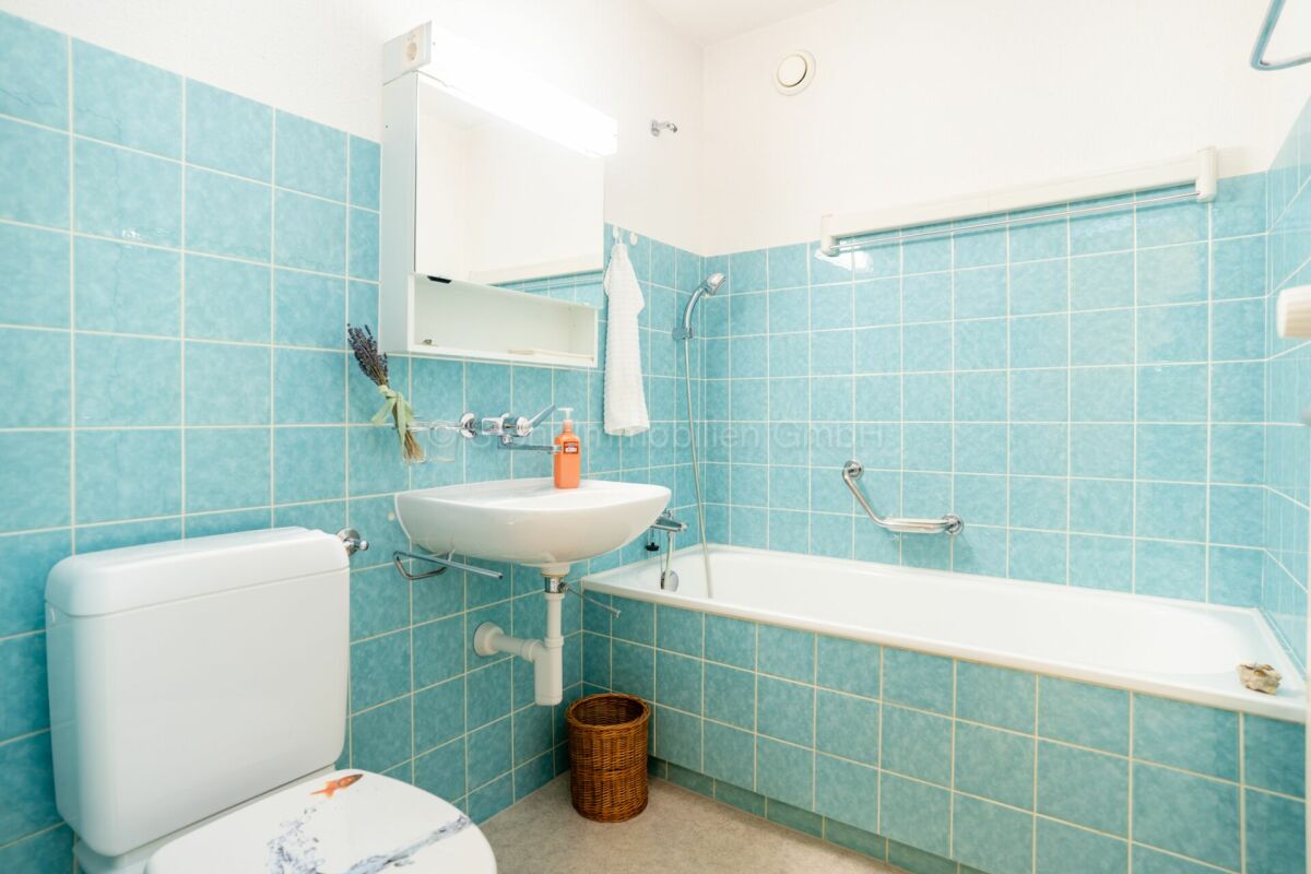 Kleines blaues Badezimmer mit Wanne und Waschbecken