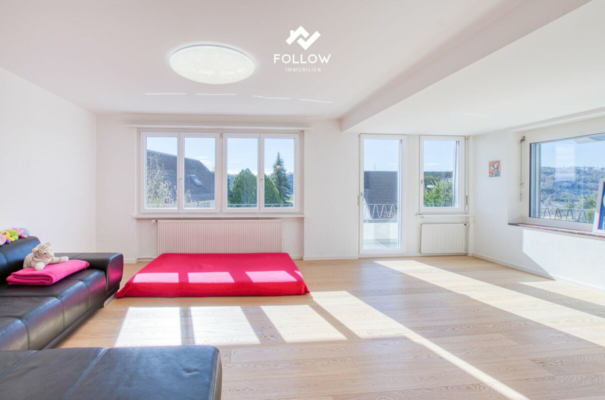 Helles Wohn- oder Schlafzimmer mit großen Fenstern und Sofa