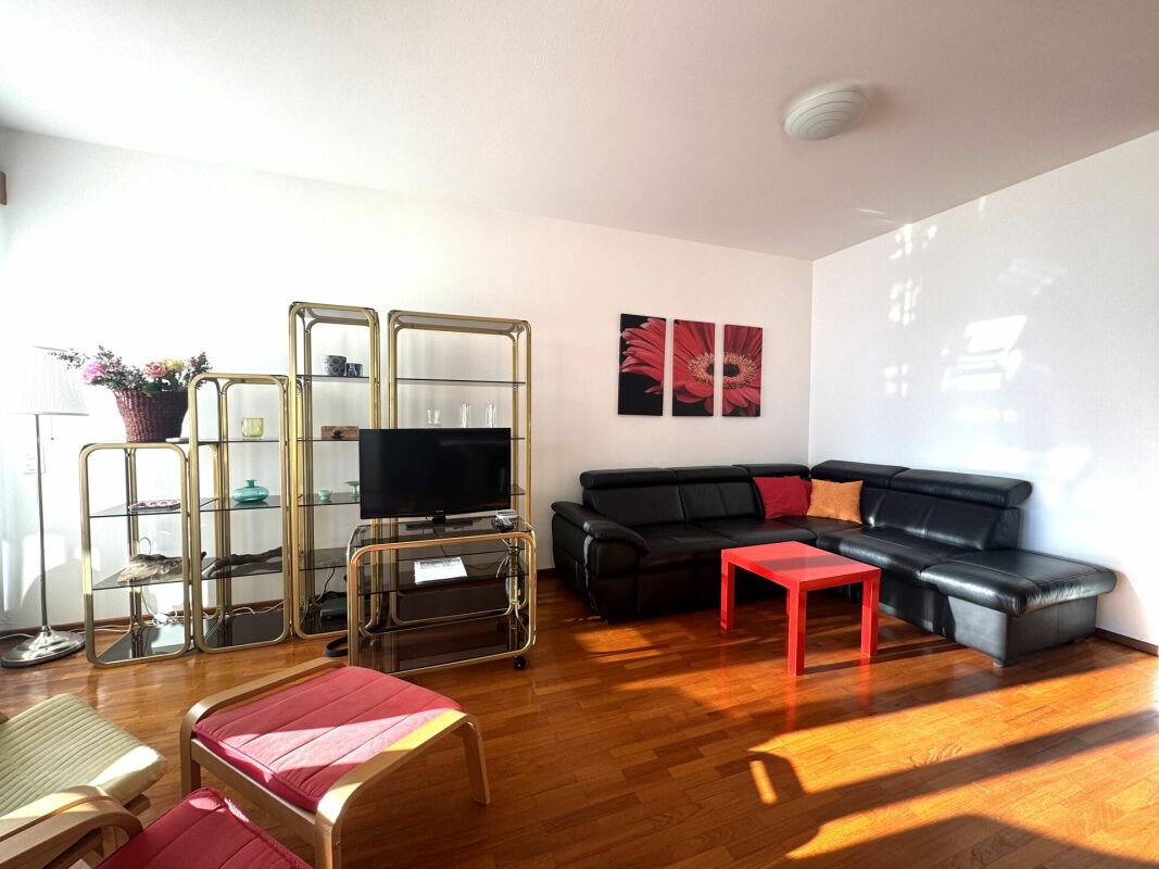 Helles Wohnzimmer mit schwarzer Eckcouch und goldfarbenem Regal
