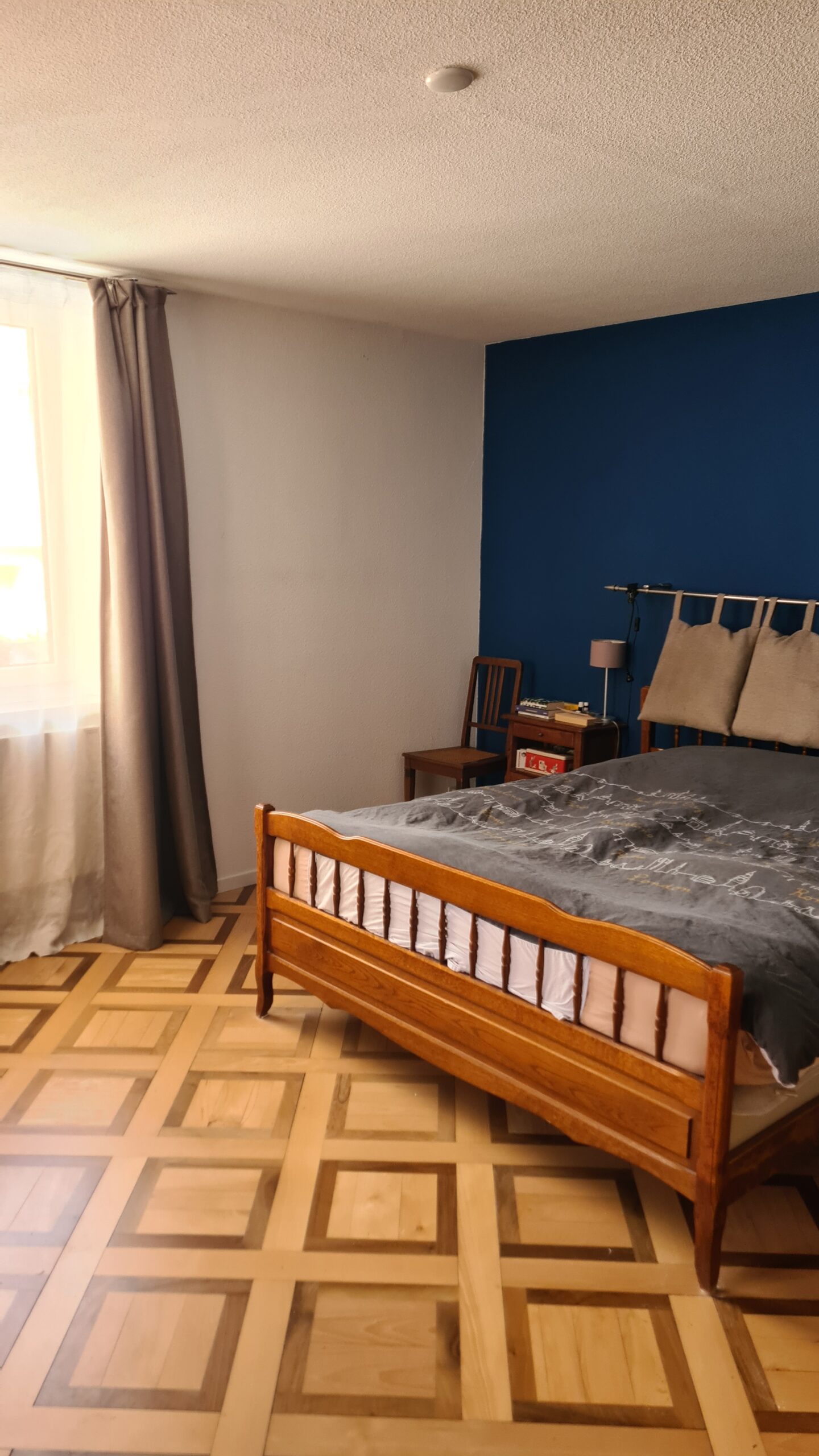 Schlafzimmer mit Holzbett und blau akzentuierter Wand