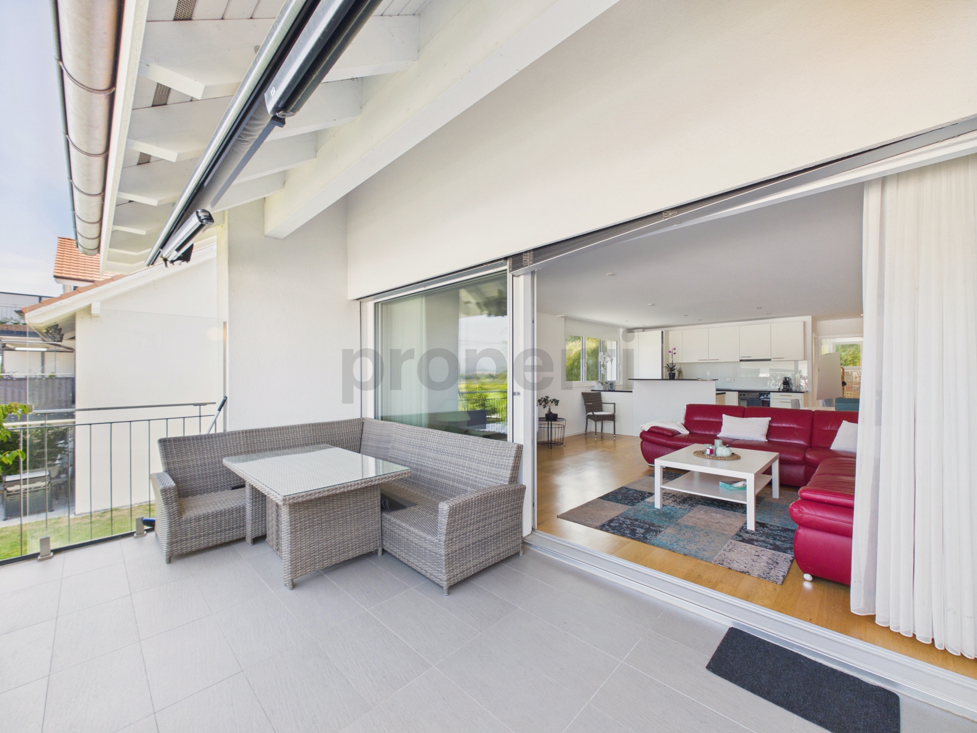 Überdachte Terrasse mit Blick ins offene Wohnzimmer