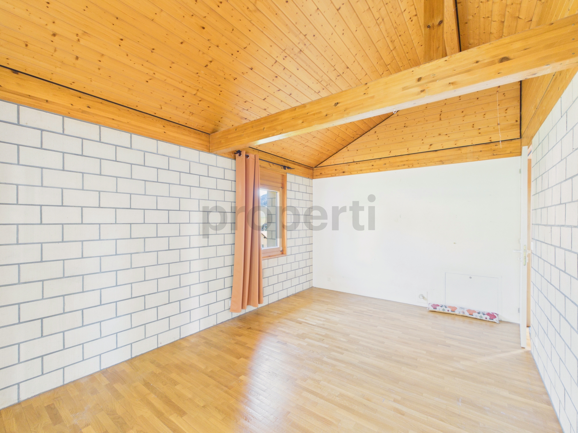 Leerer Wohnraum mit Holzdach und Parkettboden