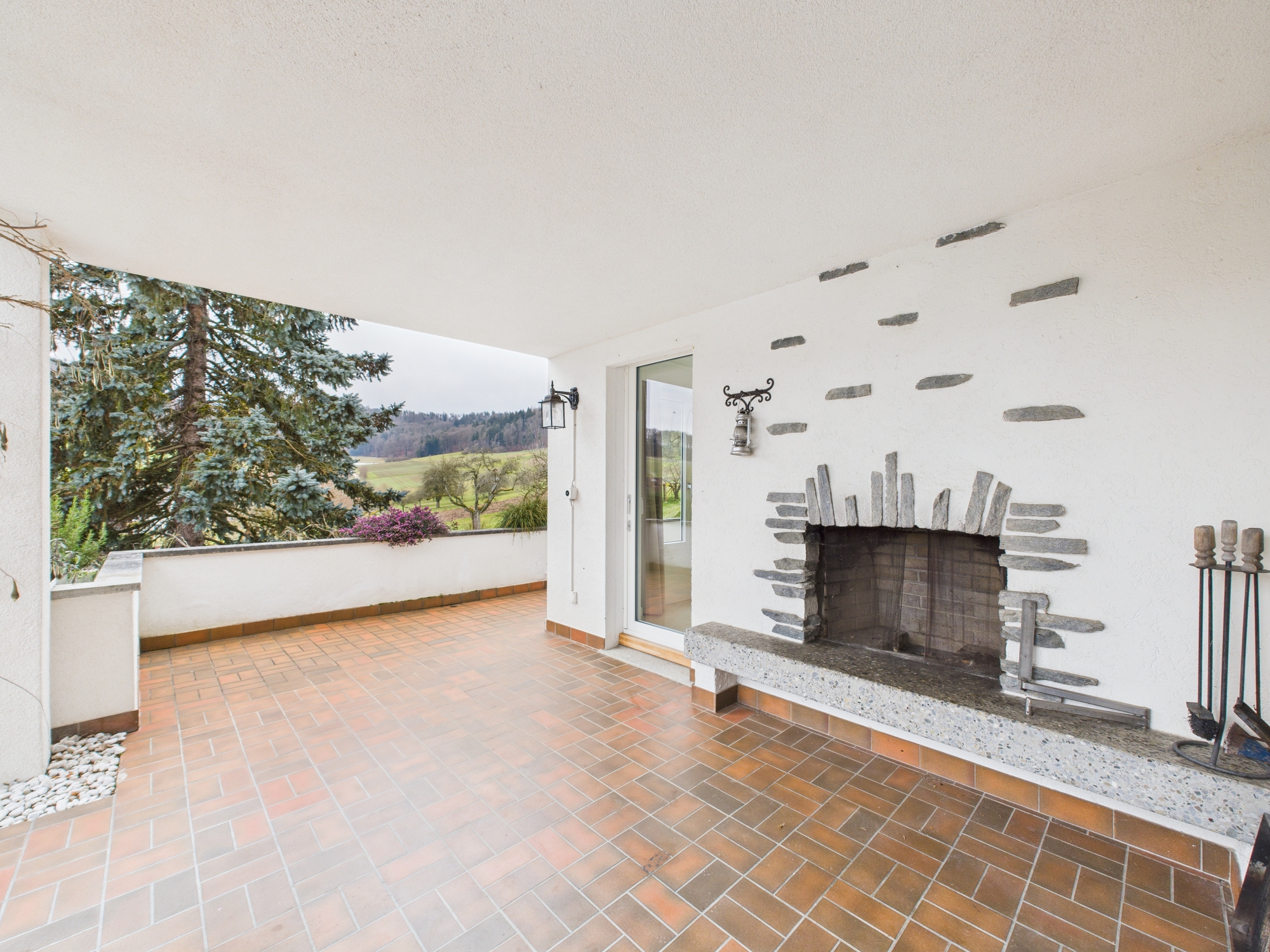 Überdachte Terrasse mit Kamin und Landschaftsblick