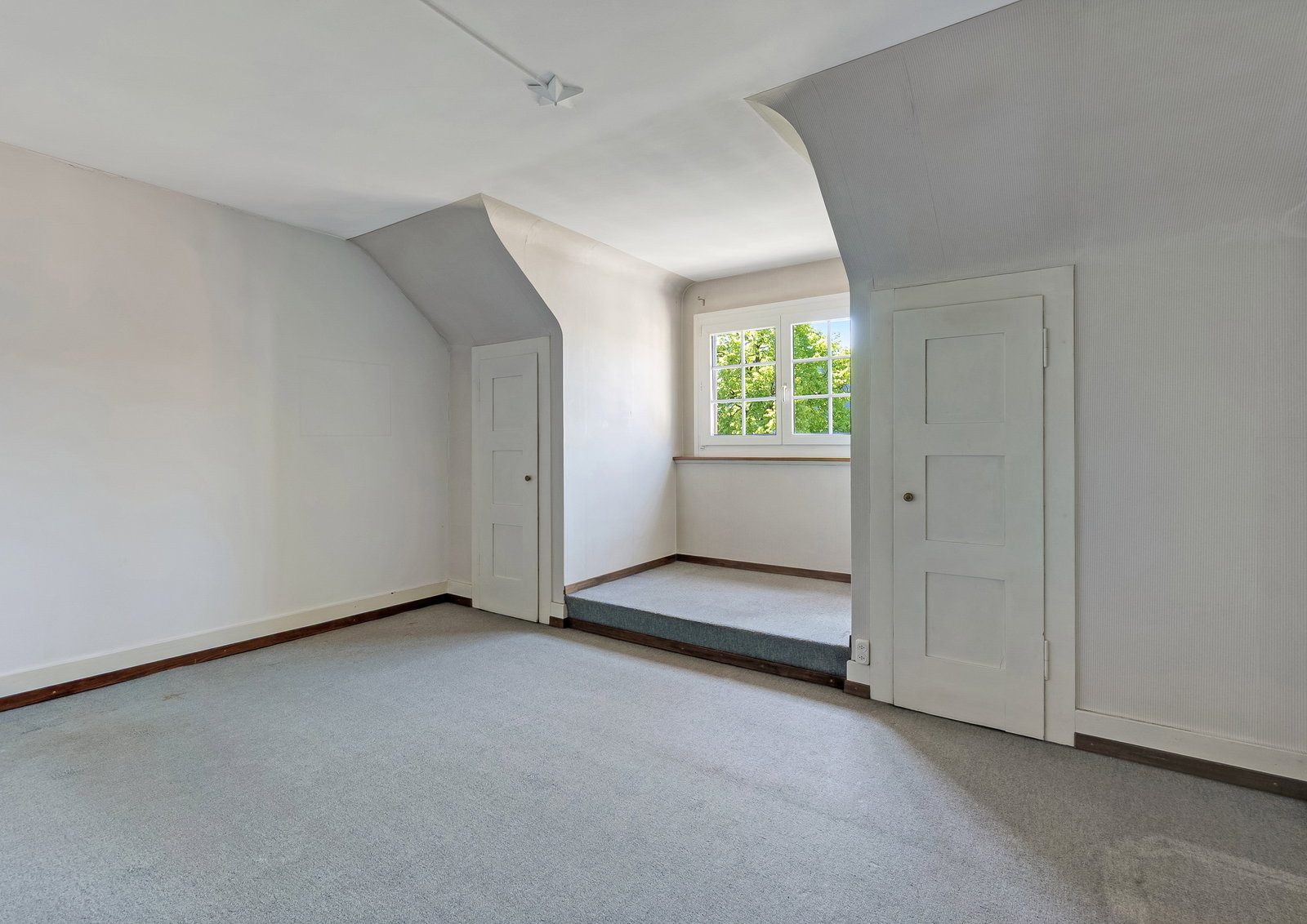 Heller Raum mit Teppichboden und zwei kleinen Türen