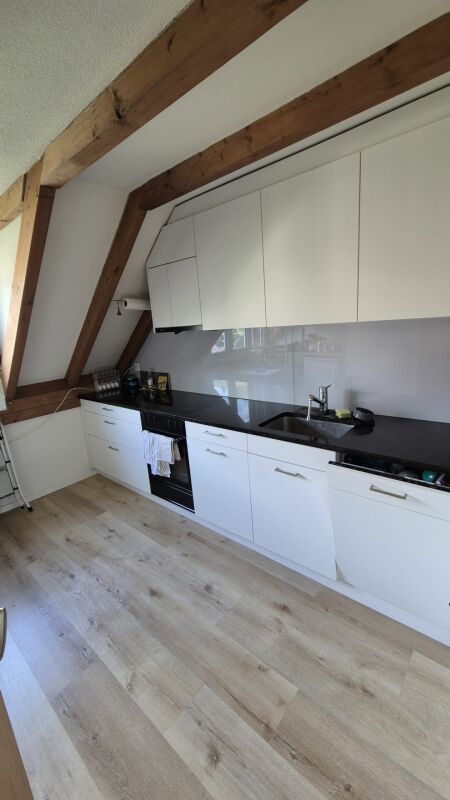 Helle Dachgeschossküche mit sichtbaren Holzbalken