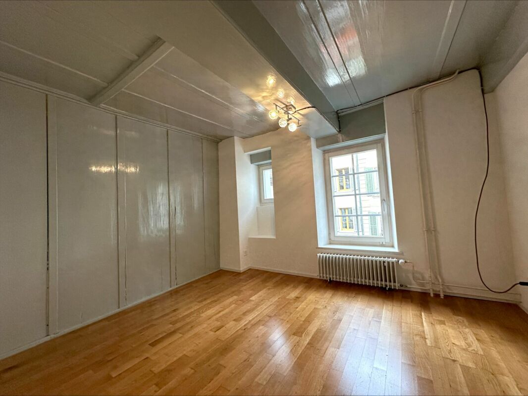 Leerer heller Raum mit Holzboden und zwei Fenstern