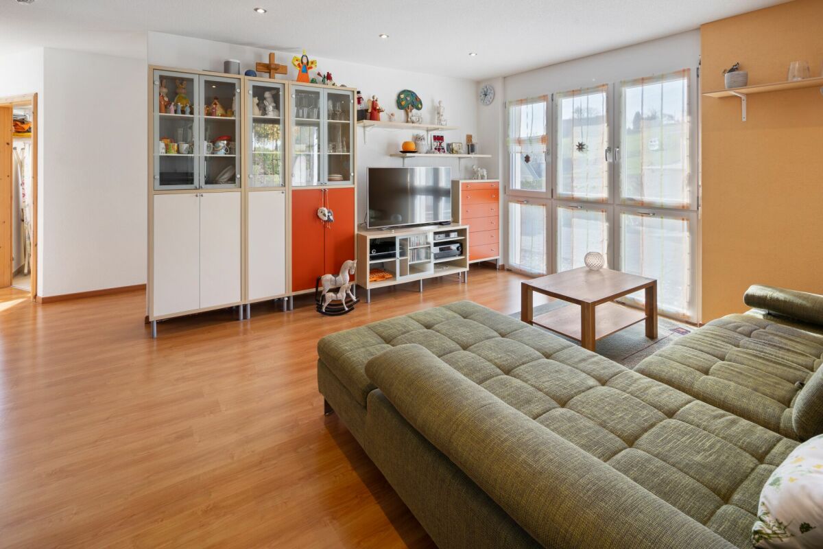 Wohnzimmer mit großen Fenstern und Wohnwand