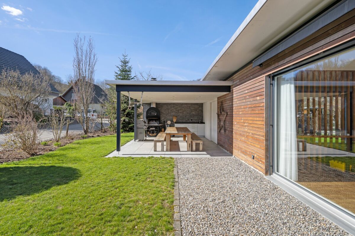 Moderner überdachter Außenbereich mit Grill und Sitzplatz