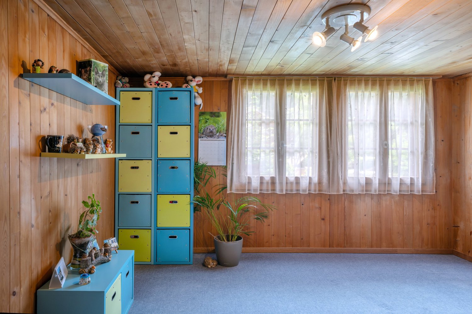 Gemütliches, holzvertäfeltes Zimmer mit bunten Aufbewahrungsmöbeln