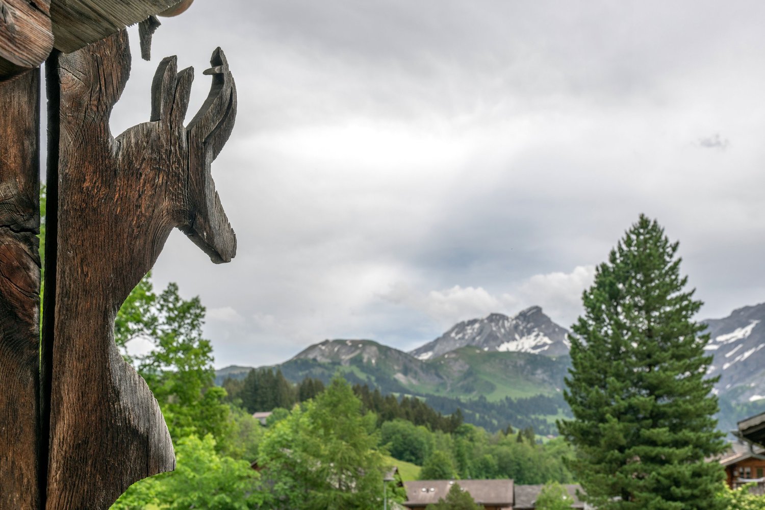 Alpenblick mit Holzskulptur im Vordergrund