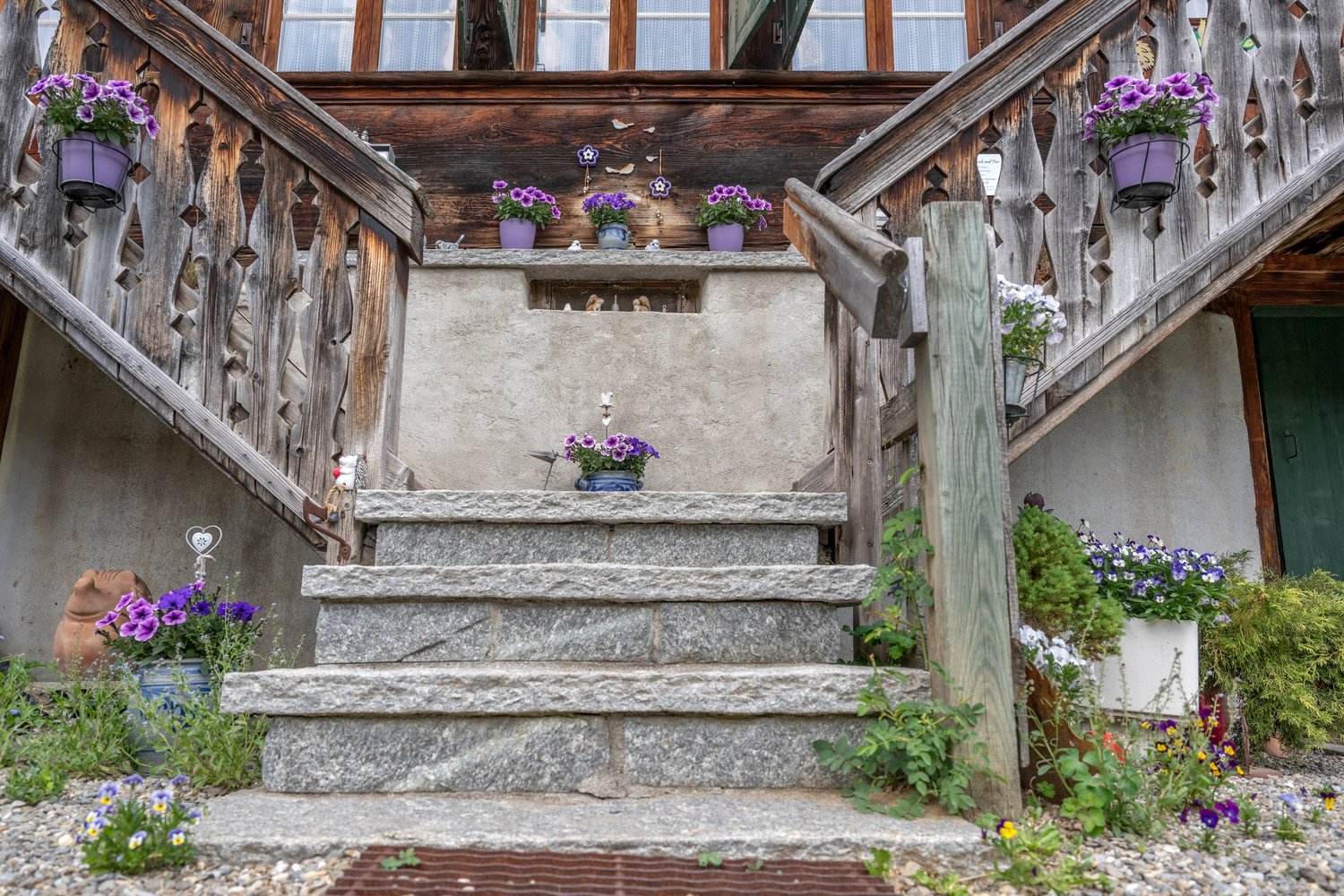Außentreppe mit rustikaler Holzbrüstung und Blumendeko