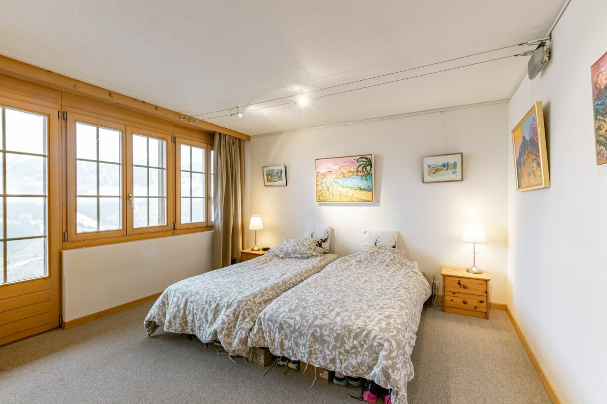 Helles Schlafzimmer mit zwei Einzelbetten und großem Holzfenster